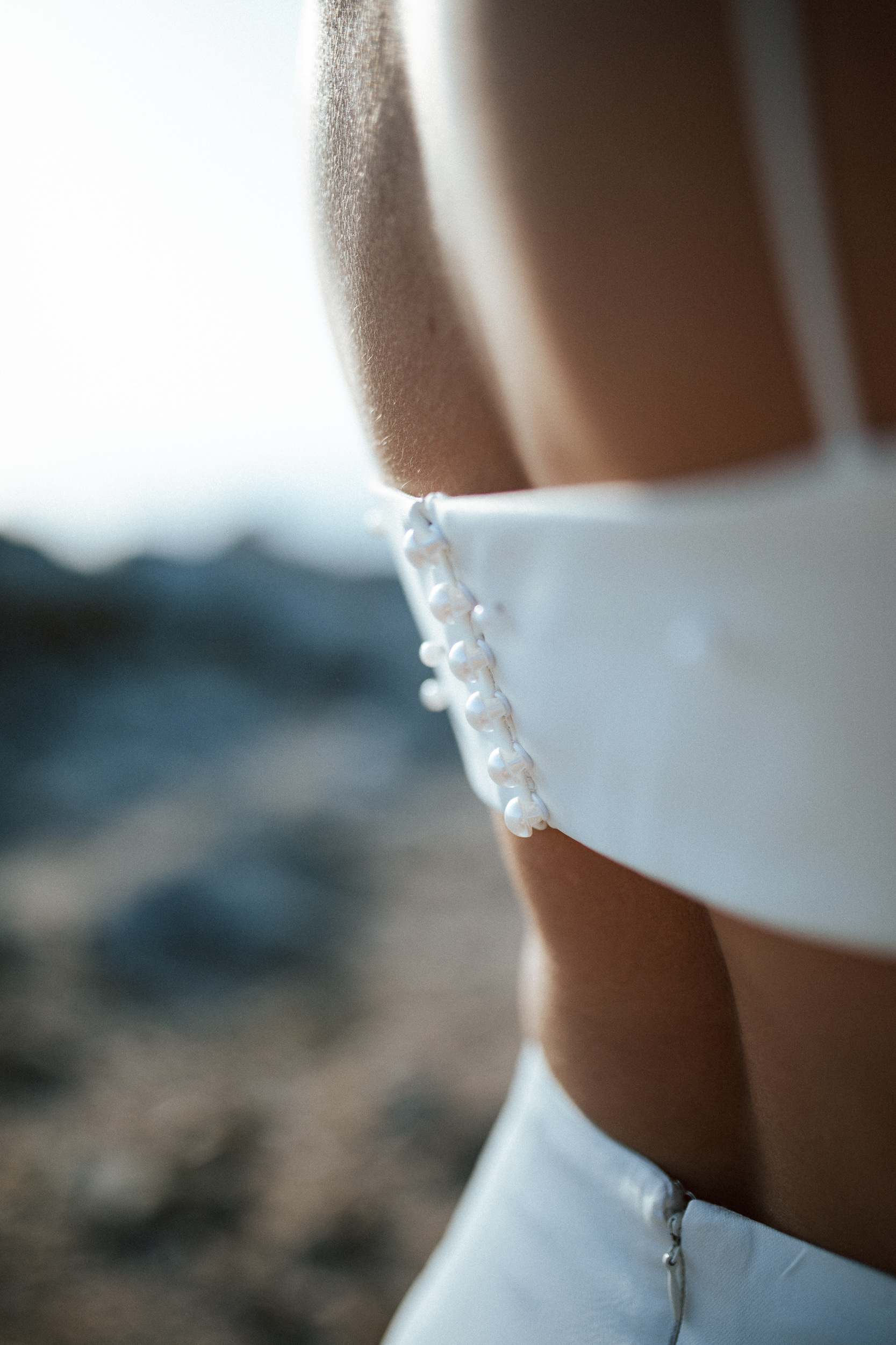 Femme rousse portant une robe de mariée brodée de perles en bord de mer.