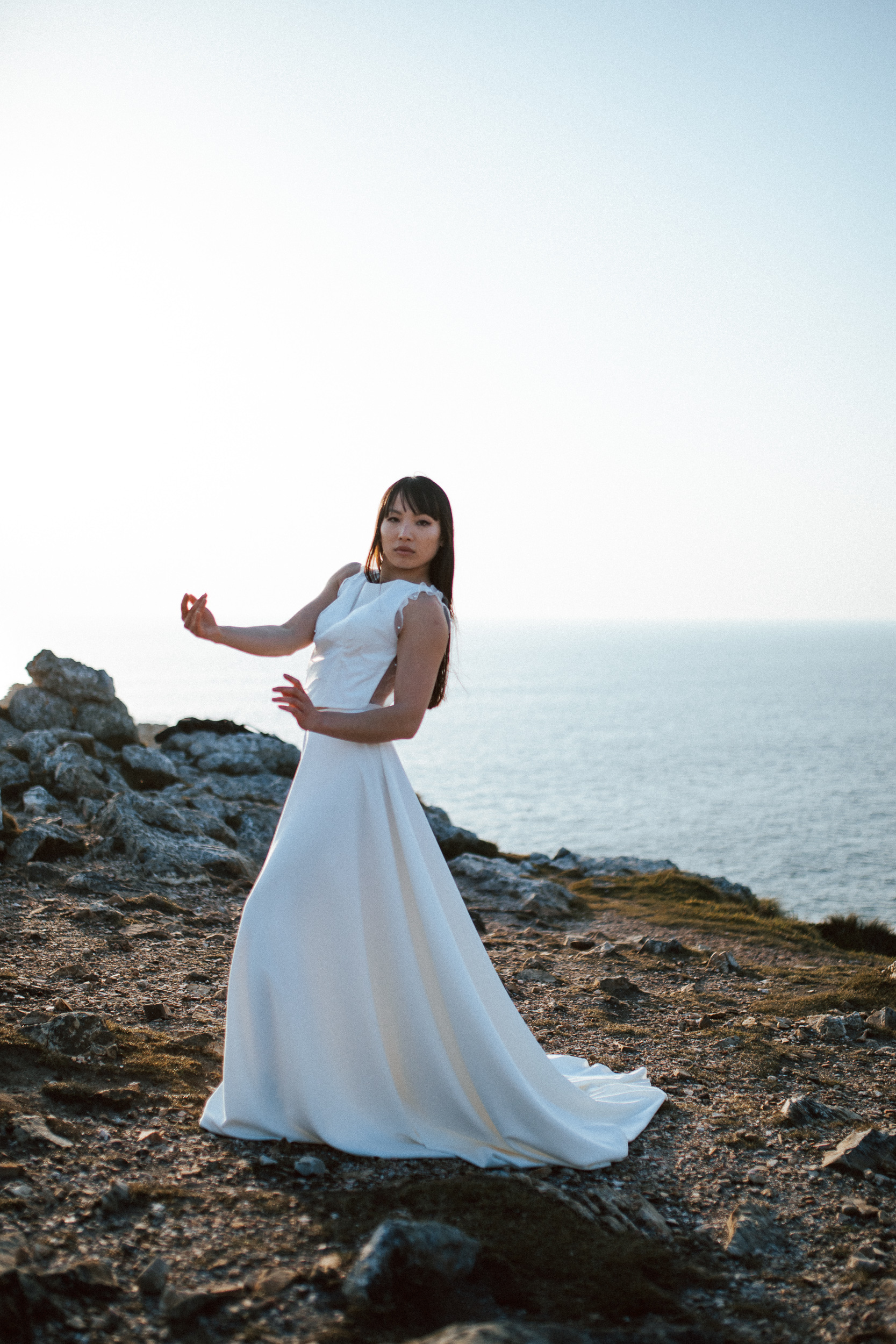 Femme asiatique portant une robe de mariée brodée de perles en bord de mer.