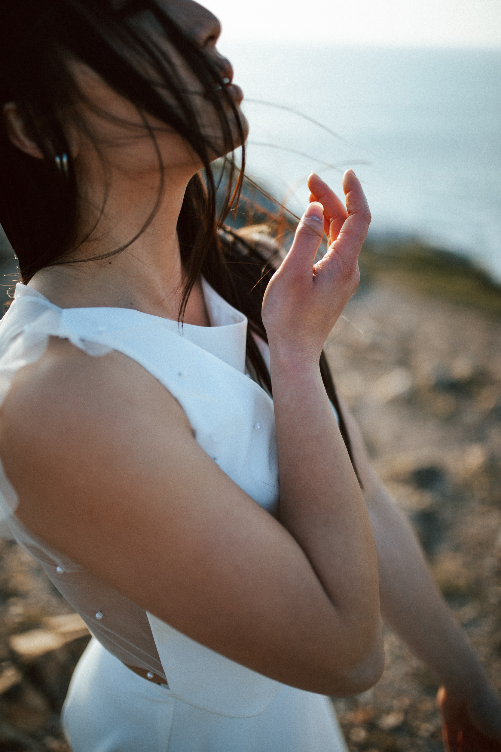 Femme asiatique portant une robe de mariée brodée de perles en bord de mer.