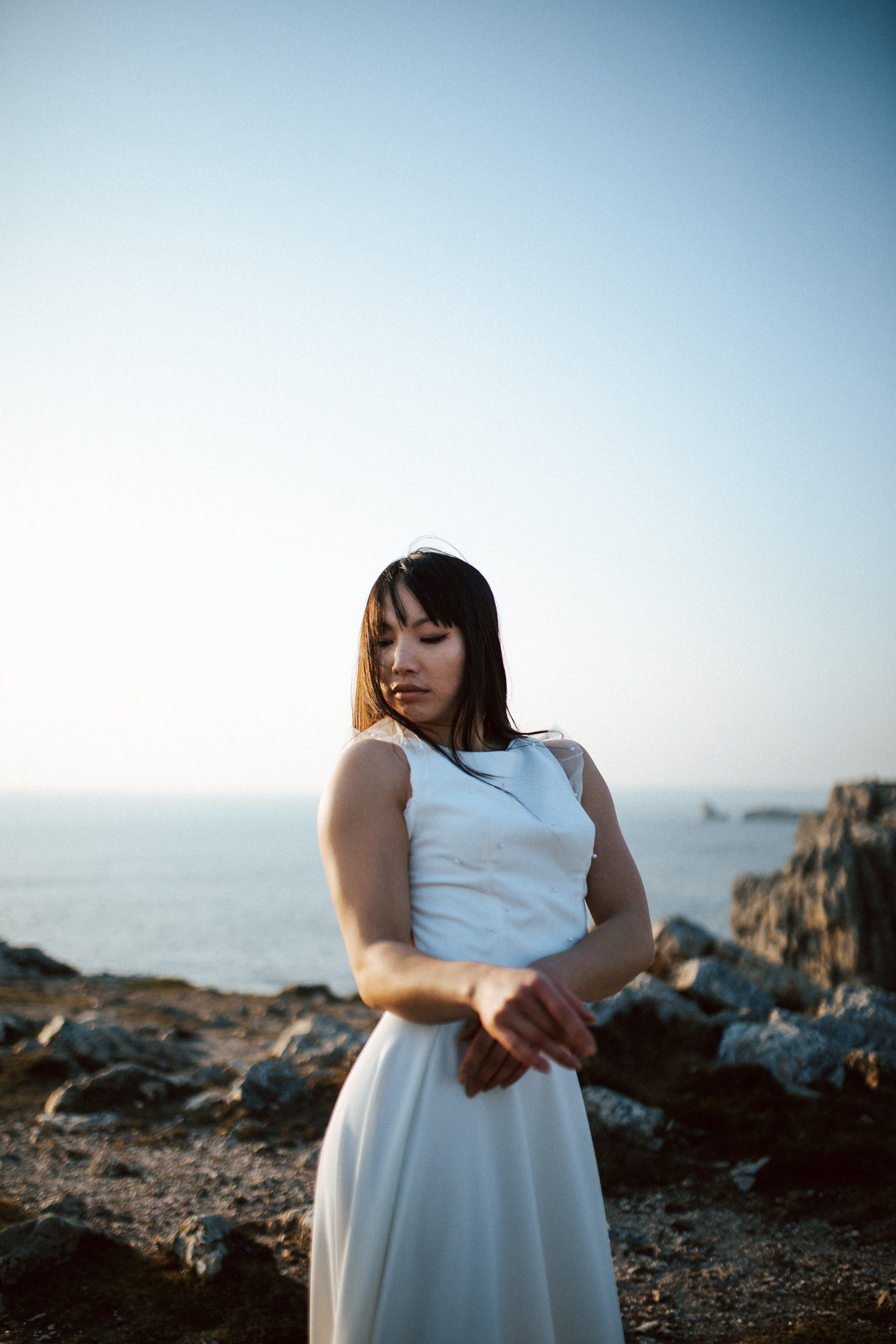 Femme asiatique portant une robe de mariée brodée de perles en bord de mer.