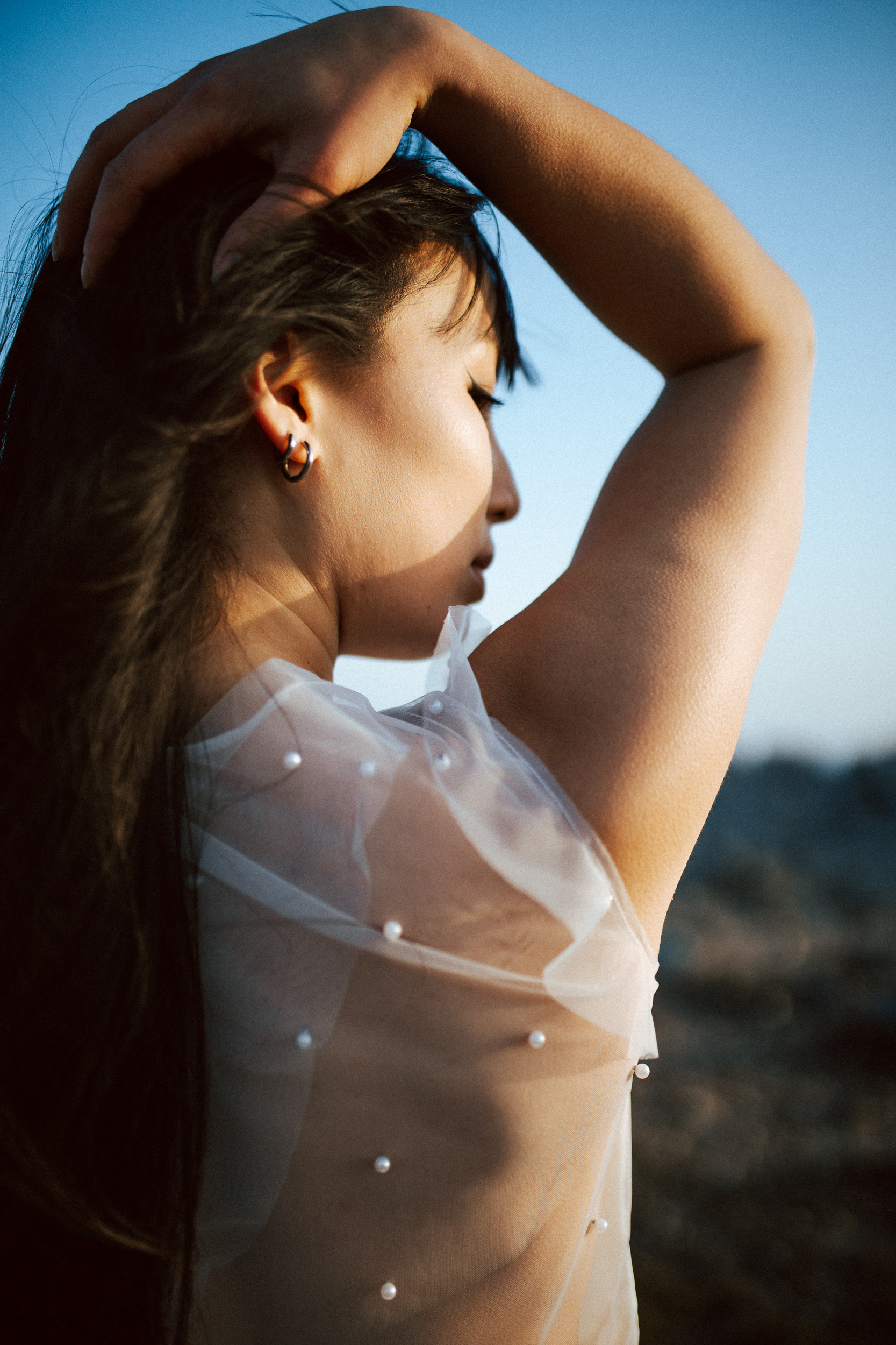 Femme asiatique portant une robe de mariée brodée de perles en bord de mer.