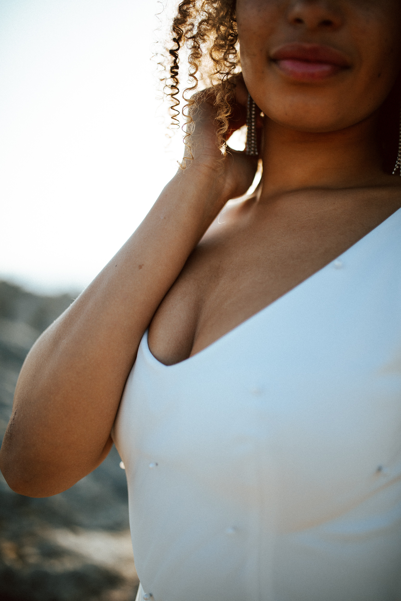 Femme métissée portant une robe de mariée brodée de perles en bord de mer.