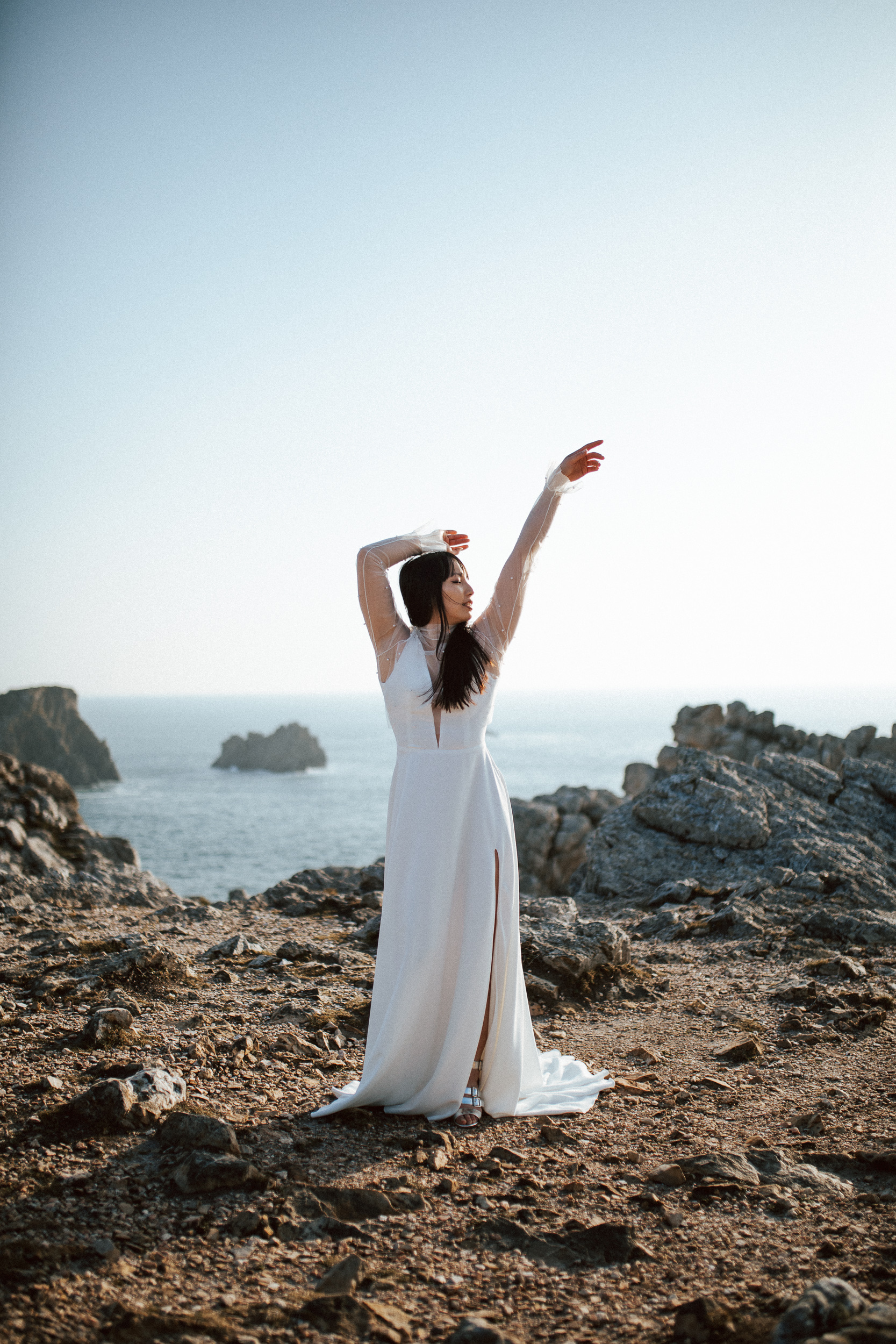 Femme asiatique portant une robe de mariée brodée de perles en bord de mer.