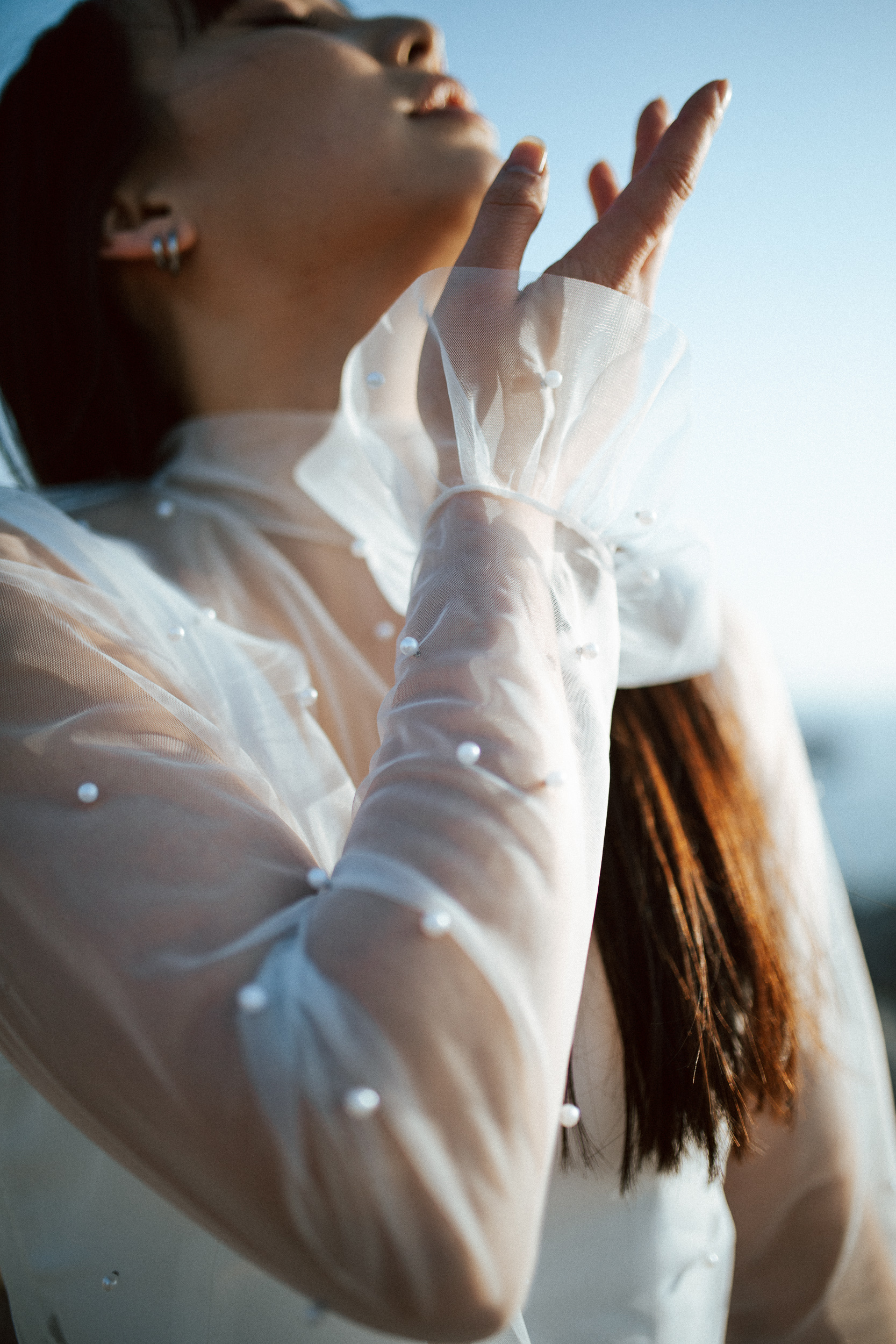 Femme asiatique portant une robe de mariée brodée de perles en bord de mer.