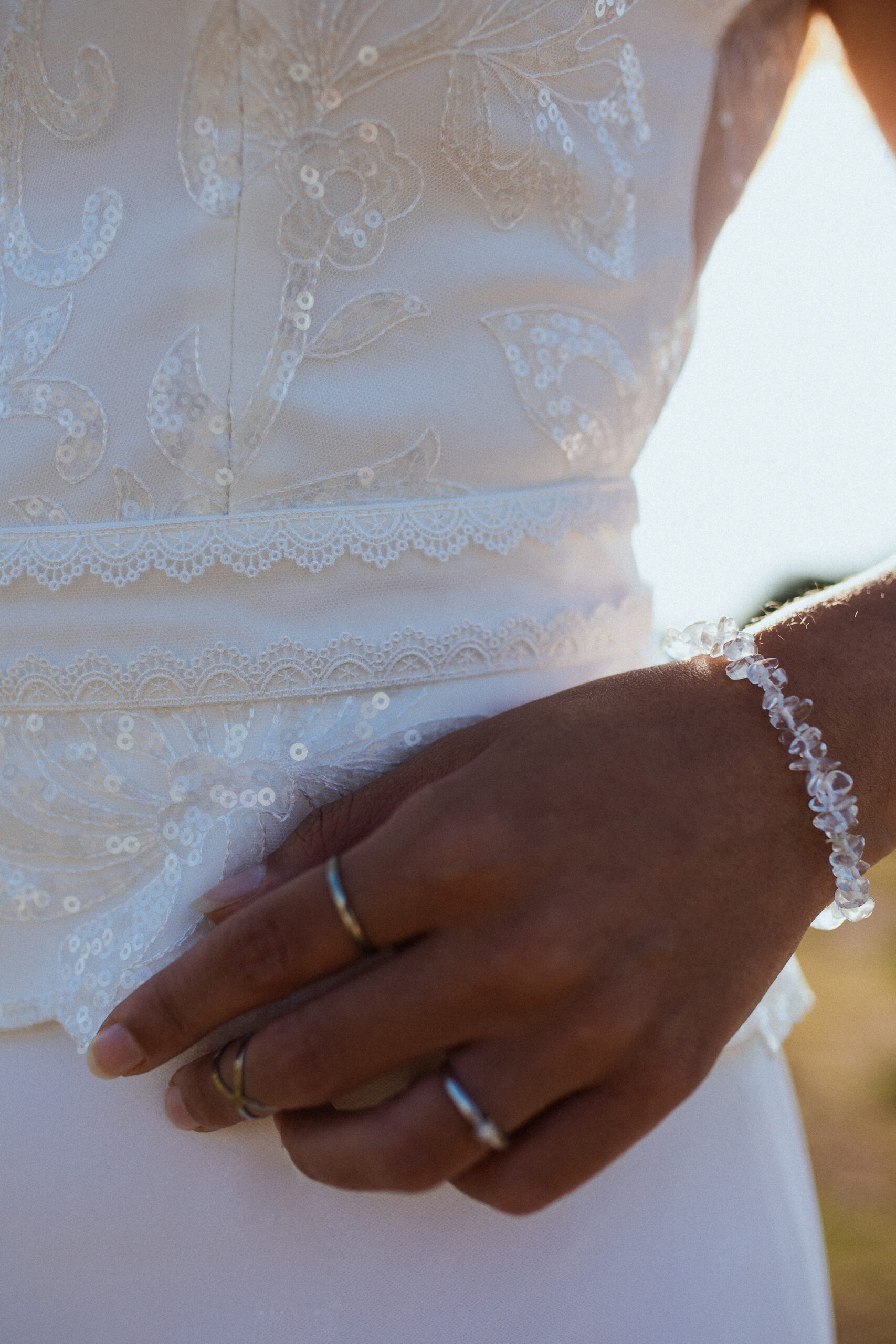 Femme rousse portant une robe de mariée en dentelle dans les dunes végétales en bord de mer.