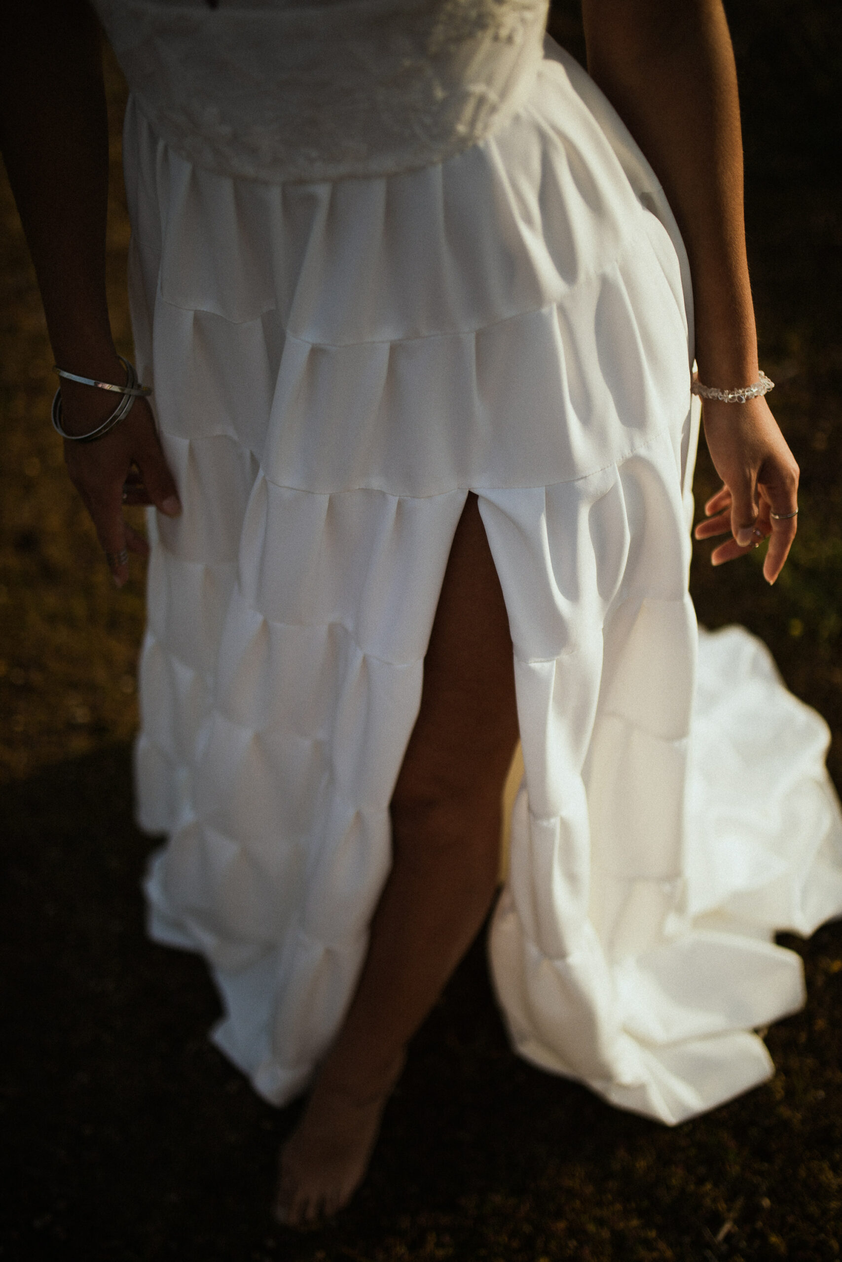 Femme rousse portant une robe de mariée en dentelle dans les dunes végétales en bord de mer.