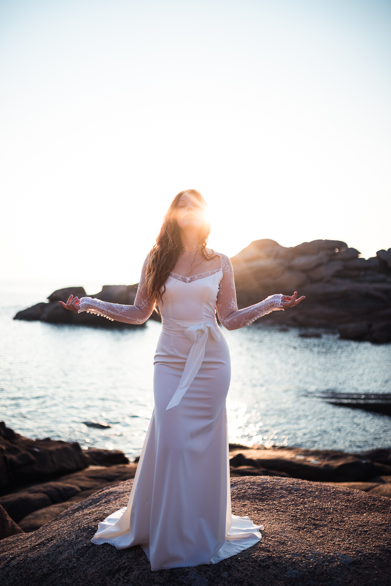 Femme portant une robe de mariée sirène en dentelle au bord de la mer en Bretagne.