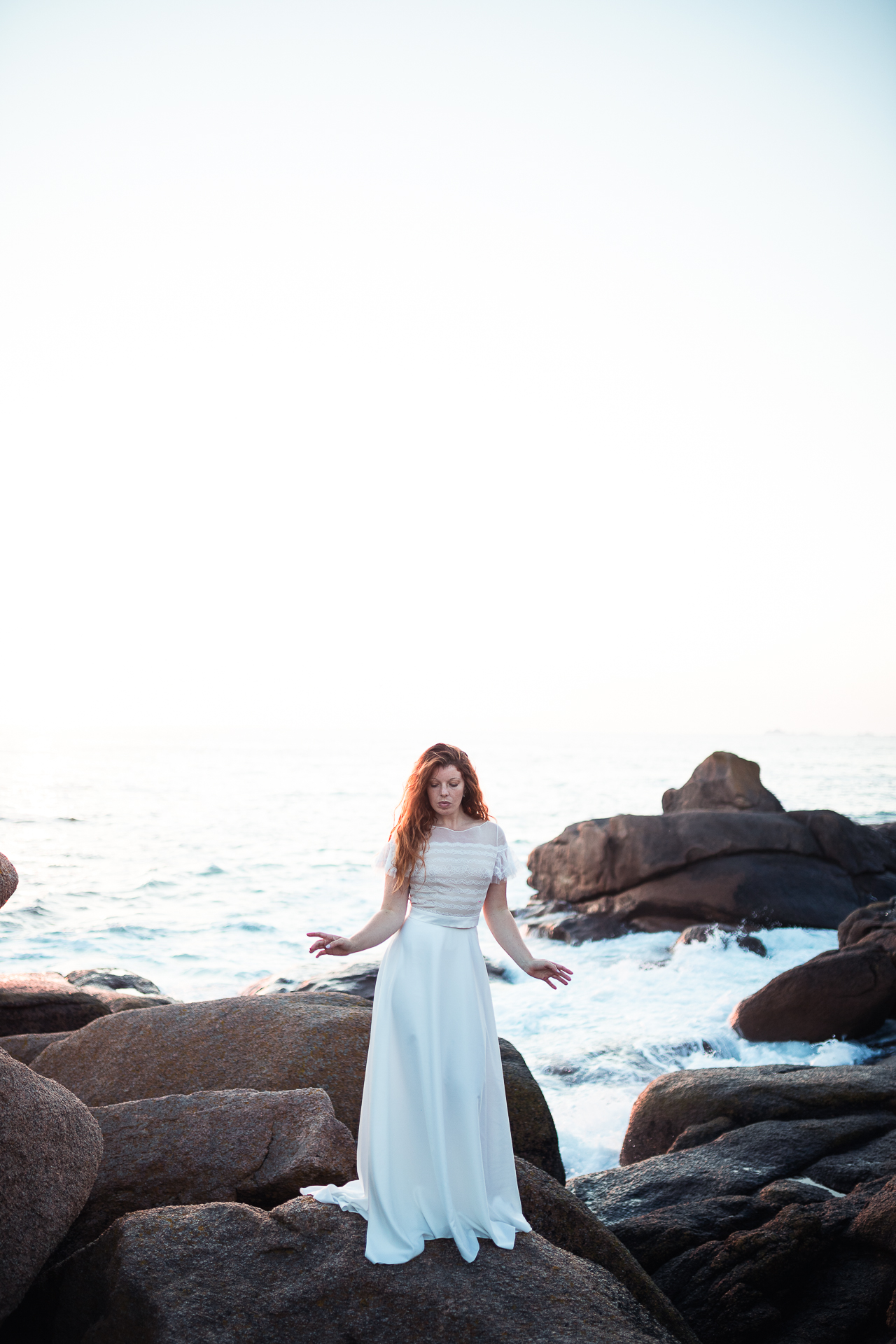 Femme portant une robe de mariée bohème au bord de la mer en Bretagne.