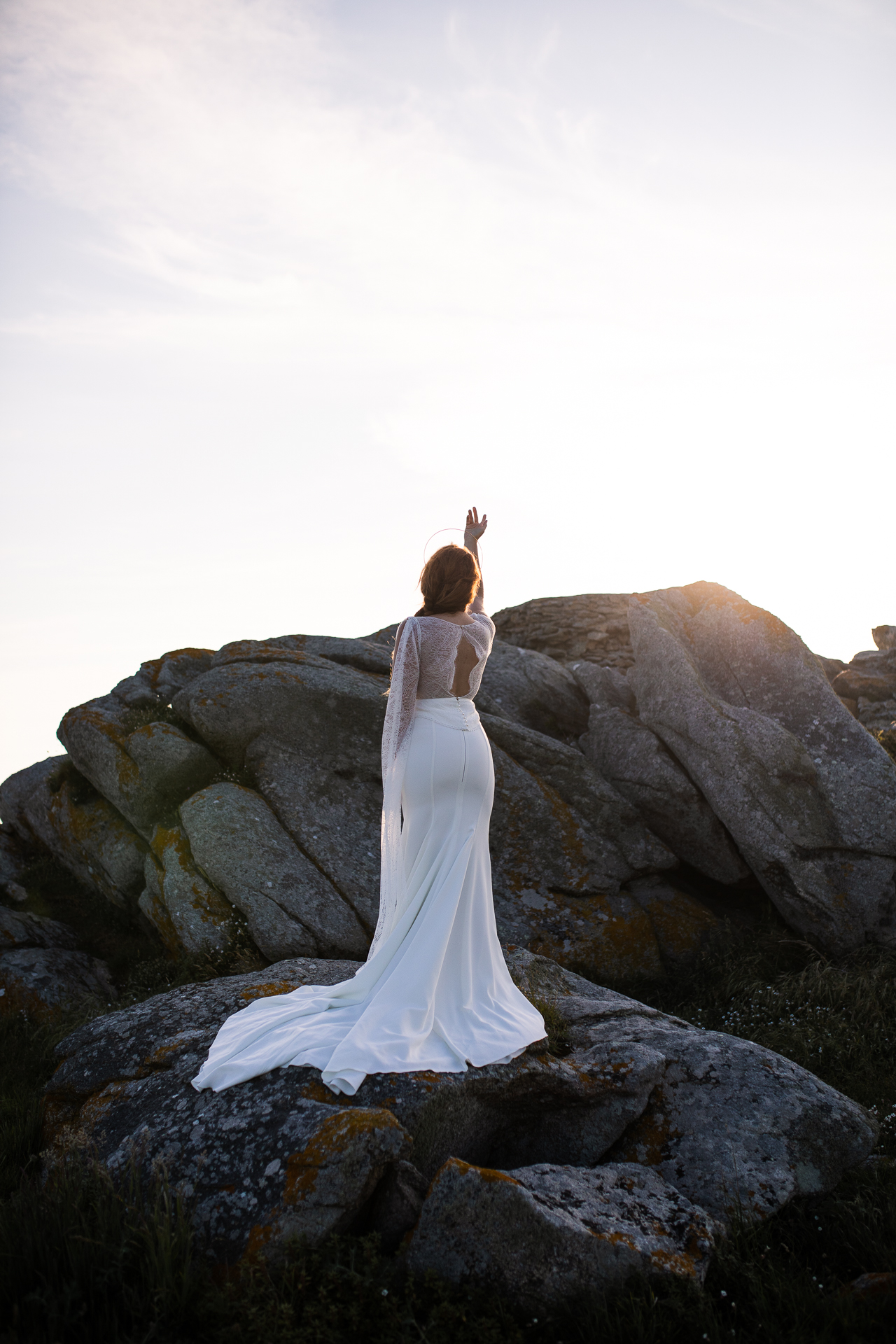 Femme portant une robe de mariée en dentelle au bord de la mer en Bretagne.