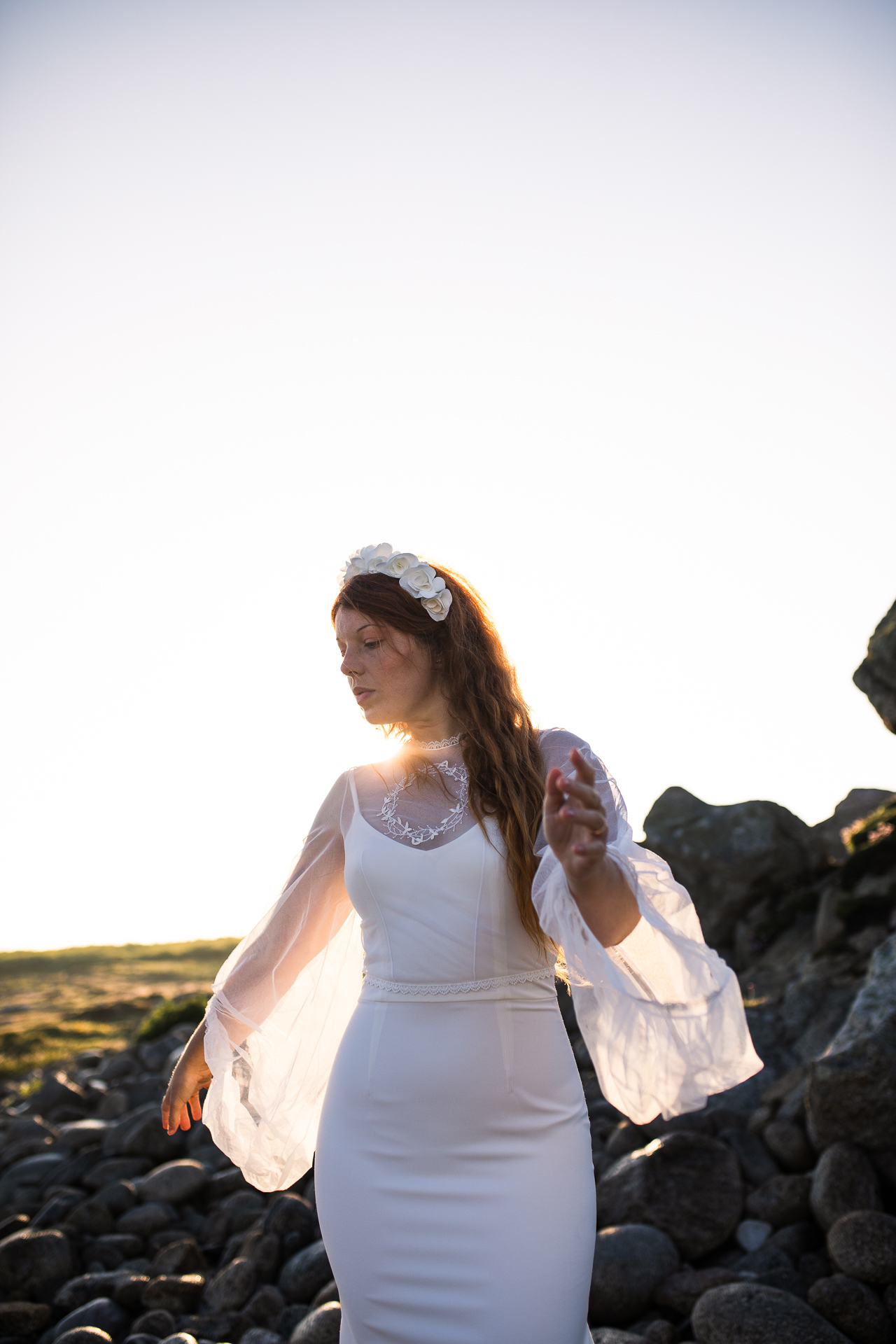 Femme portant une robe de mariée en dentelle au bord de la mer en Bretagne.