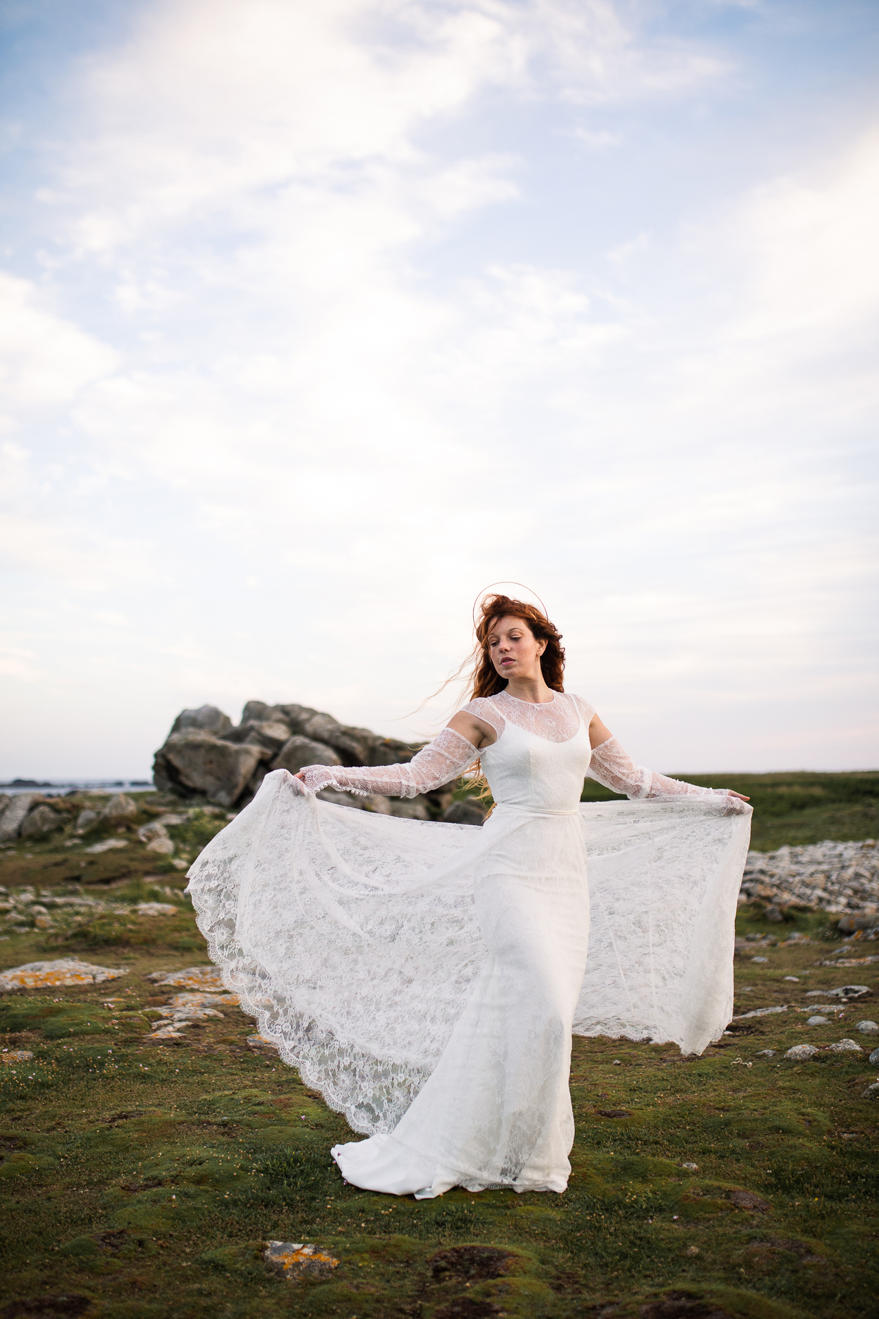 Femme portant une robe de mariée en dentelle au bord de la mer en Bretagne.