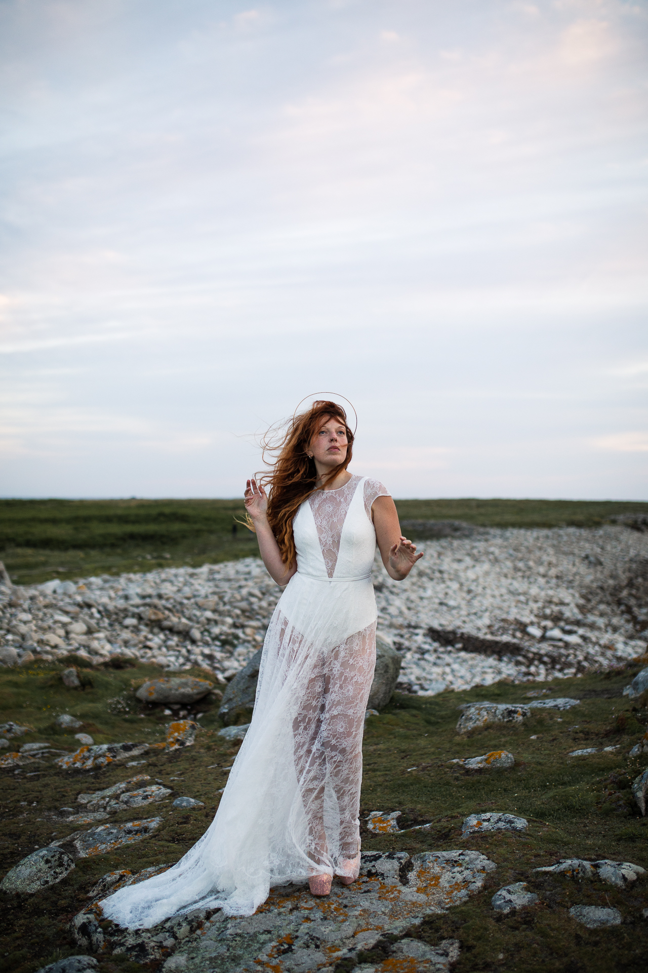 Femme portant une robe de mariée en dentelle au bord de la mer en Bretagne.