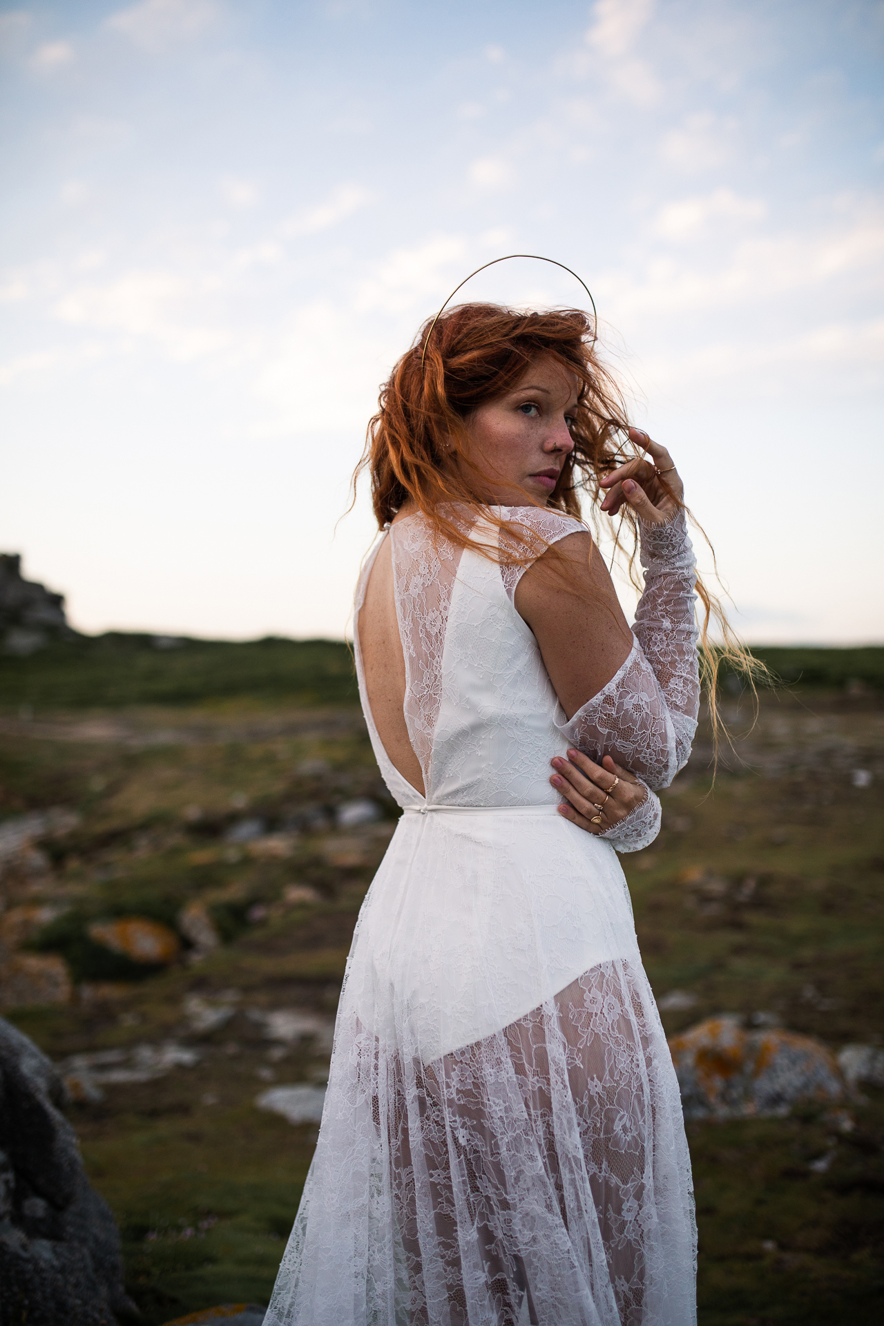 Femme portant une robe de mariée en dentelle au bord de la mer en Bretagne.