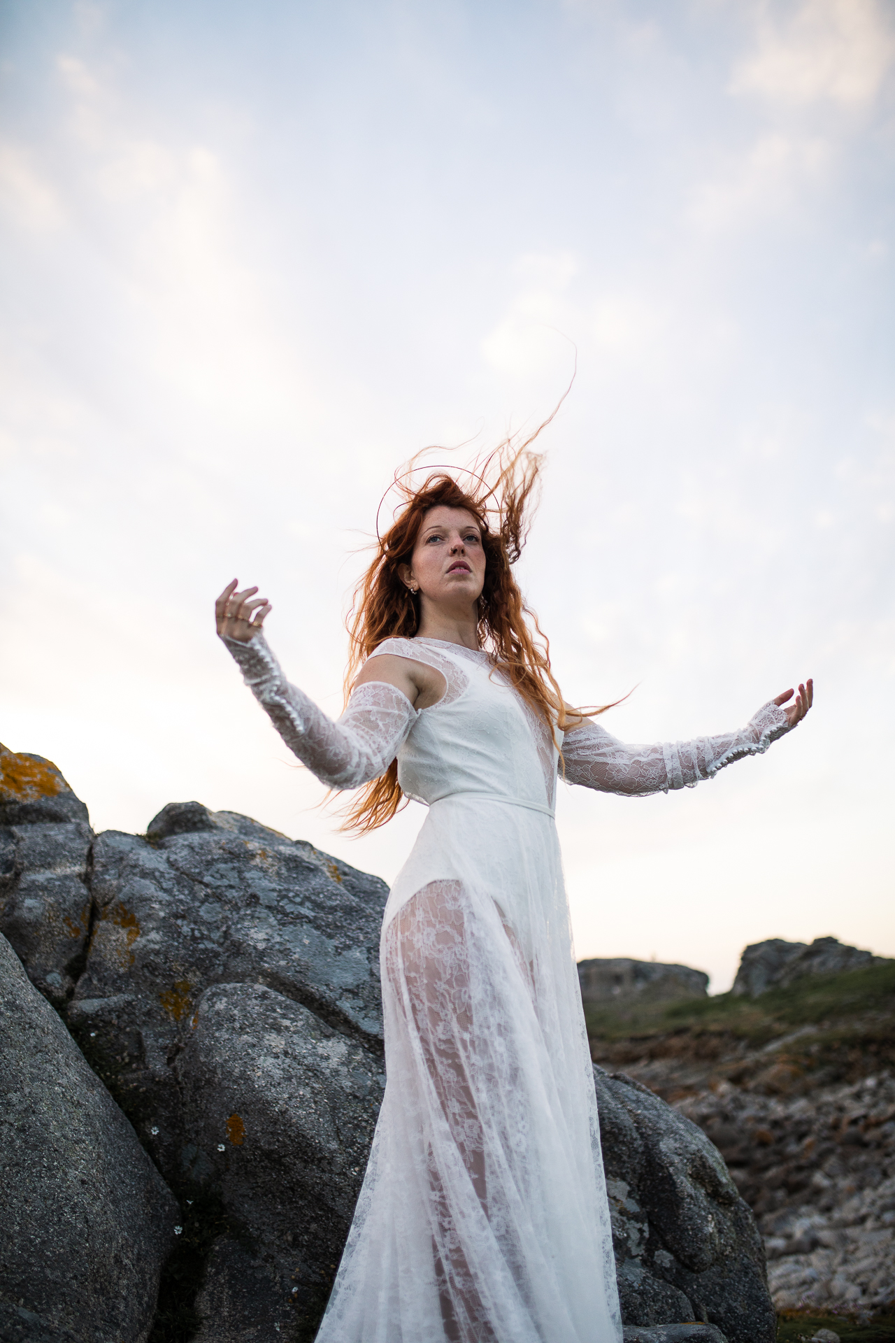 Femme portant une robe de mariée en dentelle au bord de la mer en Bretagne.