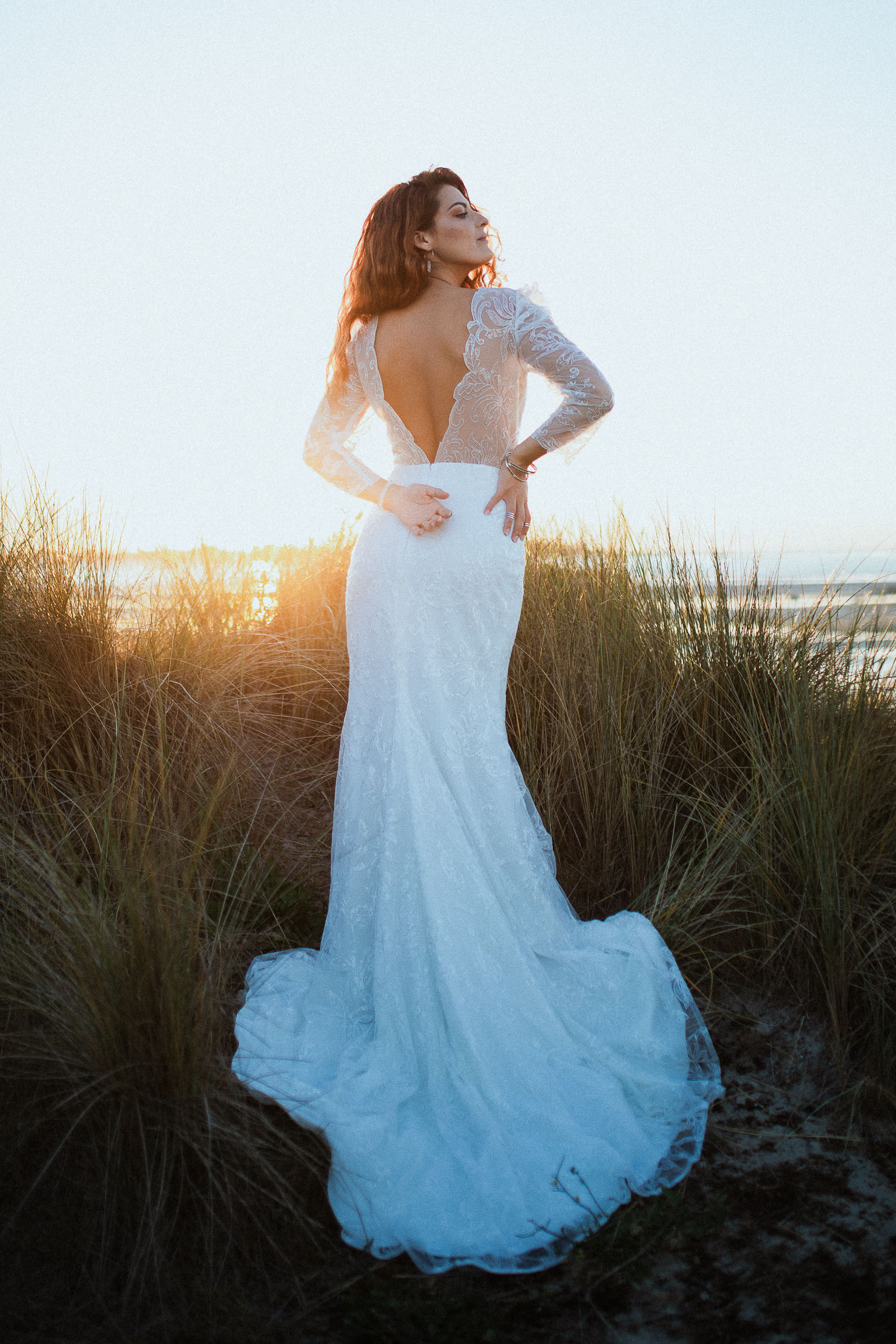 Femme portant une robe de mariée en dentelle au bord de la plage.