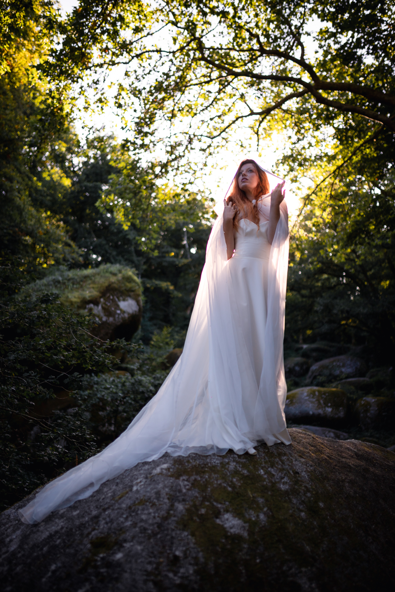 Femme portant une robe de mariée au milieu de la forêt.