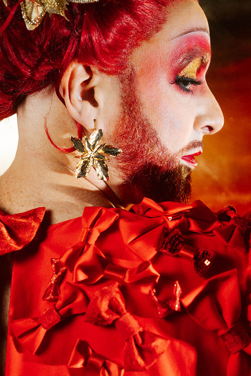 Drag queen portant une tenue de avec accumulation de nœuds rouges et or.