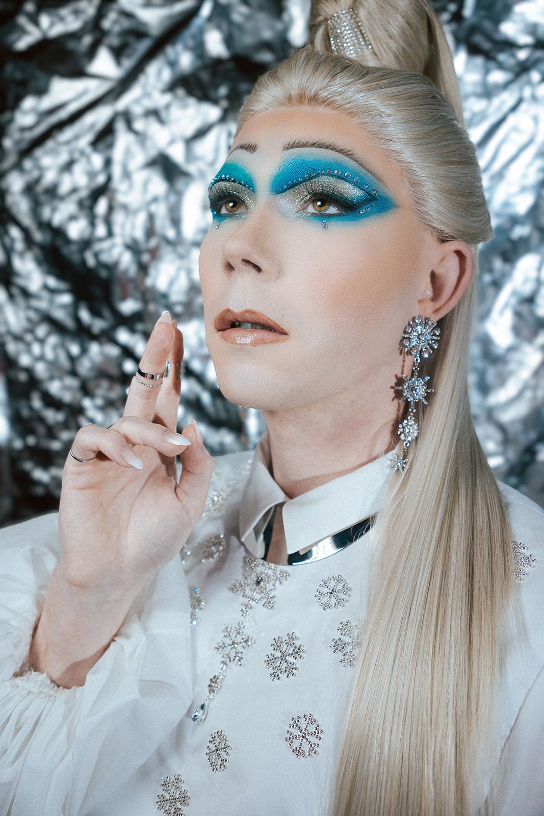 Drag queen portant une tenue de reine des glace blanche.