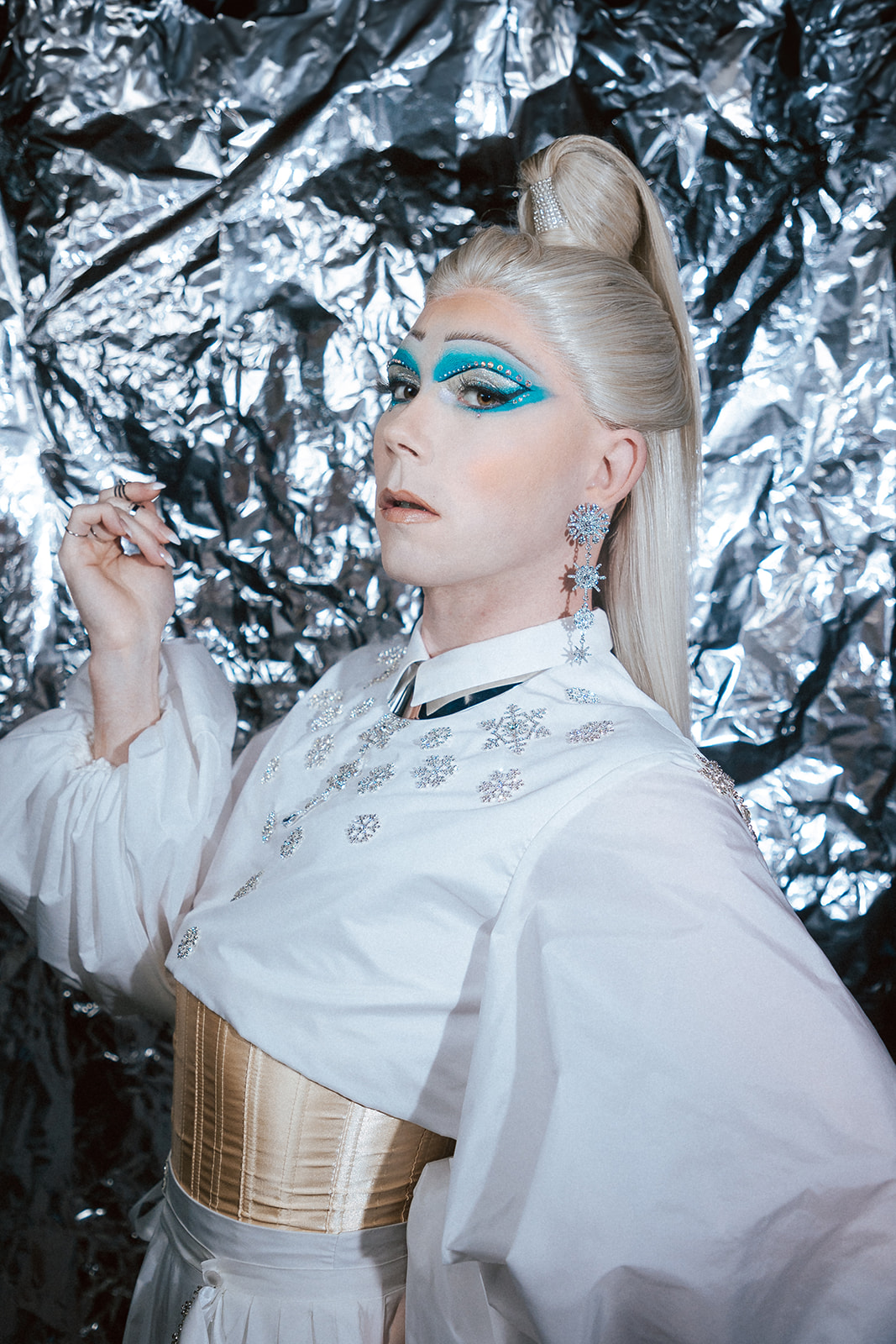 Drag queen portant une tenue de reine des glace blanche.