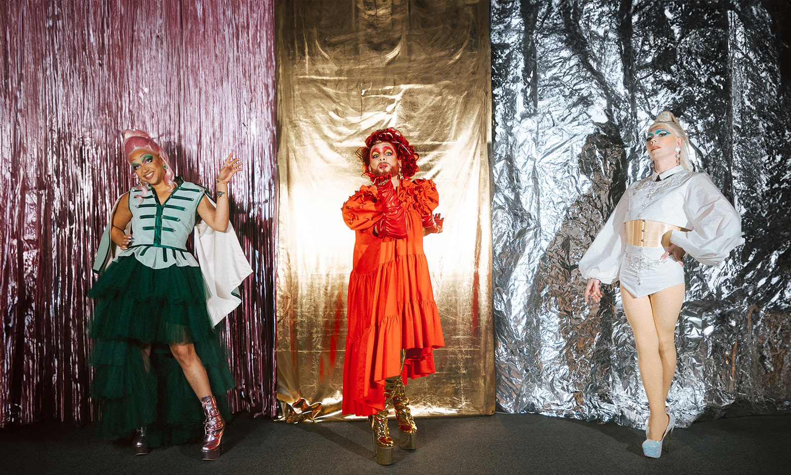 Trio de drag queen portant des tenues sur le thème de Noël.