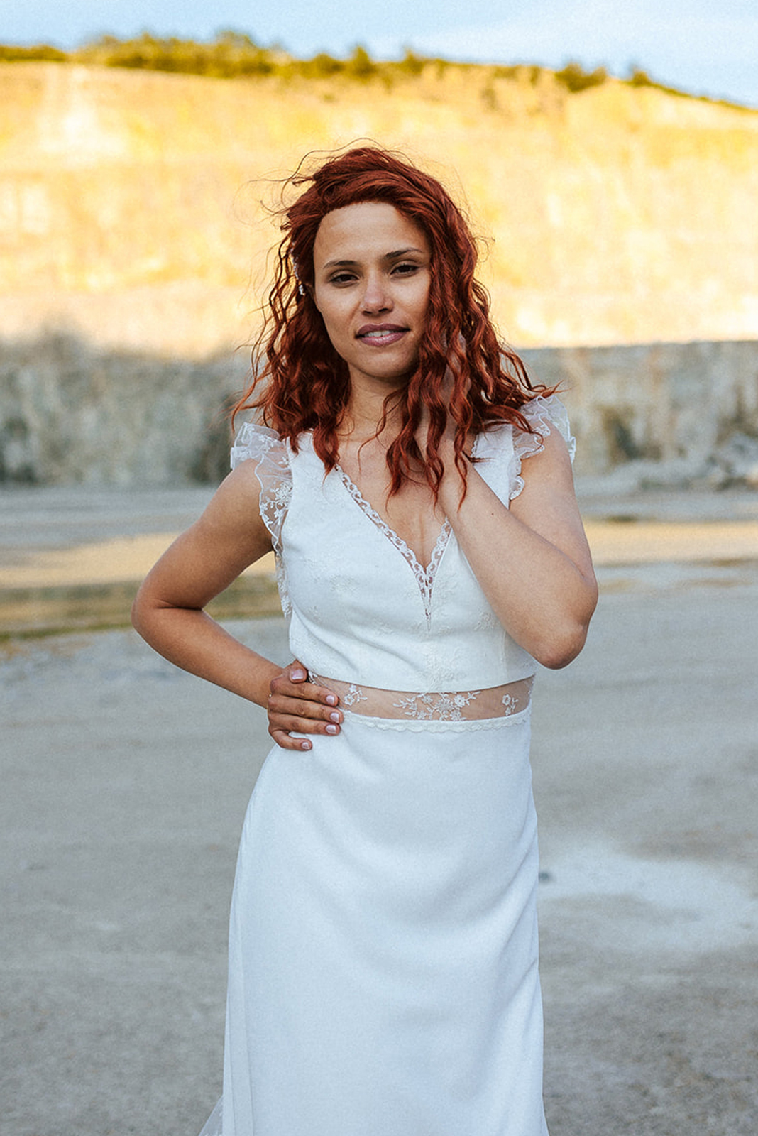 Femme rousse portant une robe de mariée bohème de créateur en dentelle sur-mesure.