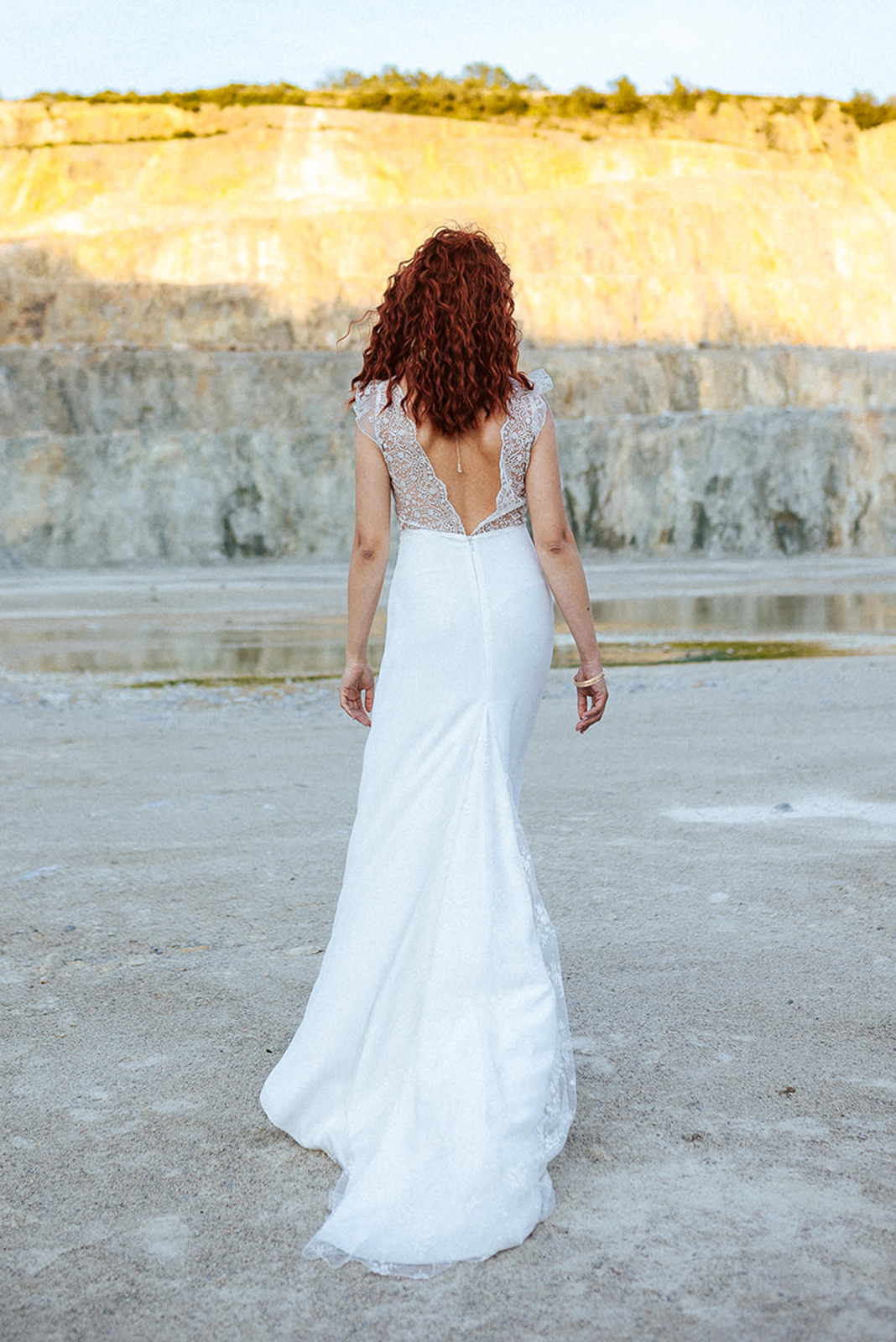 Femme rousse portant une robe de mariée bohème de créateur en dentelle sur-mesure.