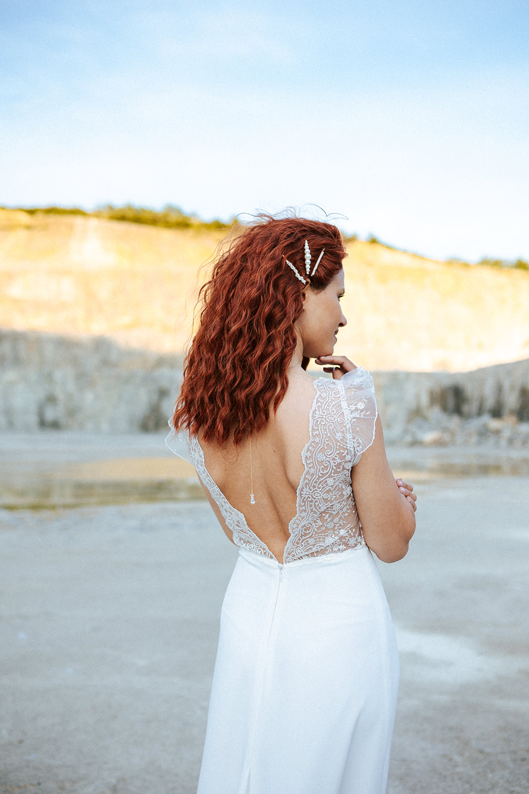 Femme rousse portant une robe de mariée bohème de créateur en dentelle sur-mesure.