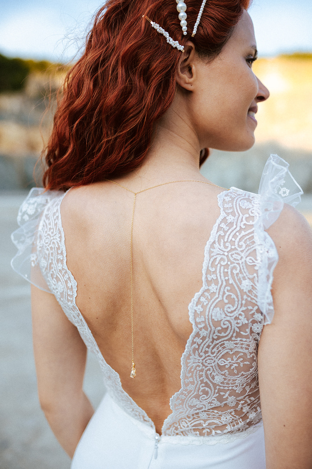 Femme rousse portant une robe de mariée bohème de créateur en dentelle sur-mesure.