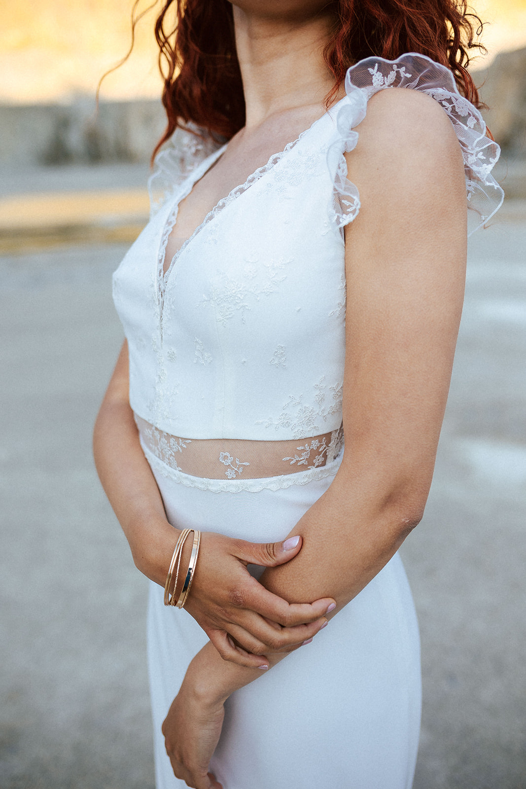 Femme rousse portant une robe de mariée bohème de créateur en dentelle sur-mesure.