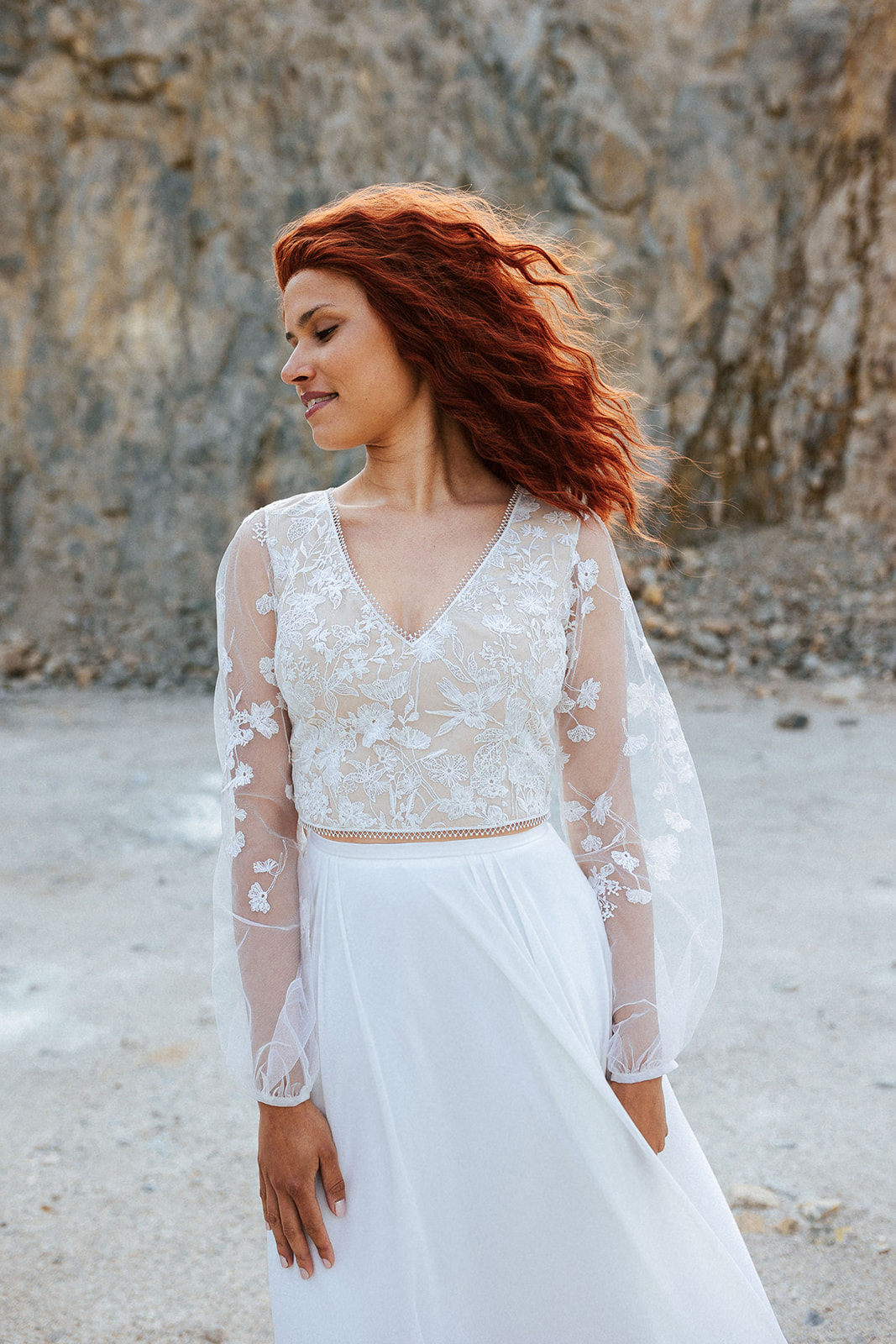Femme rousse portant une robe de mariée bohème de créateur en dentelle sur-mesure.