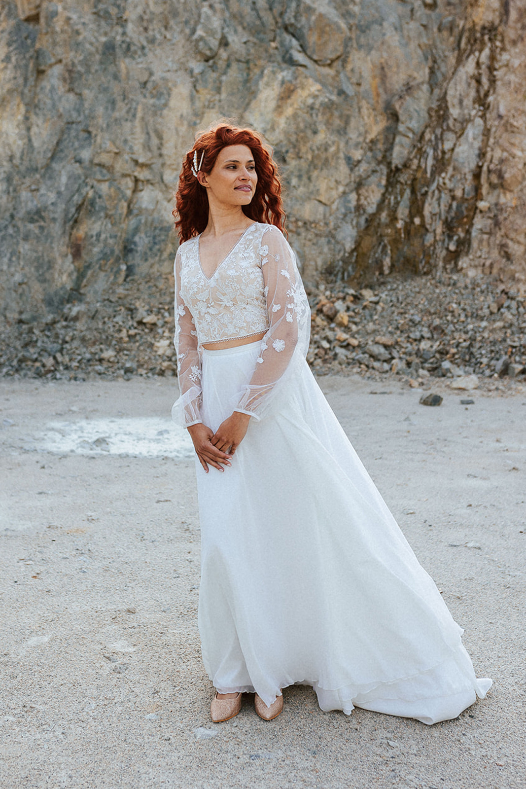 Femme rousse portant une robe de mariée bohème de créateur en dentelle sur-mesure.