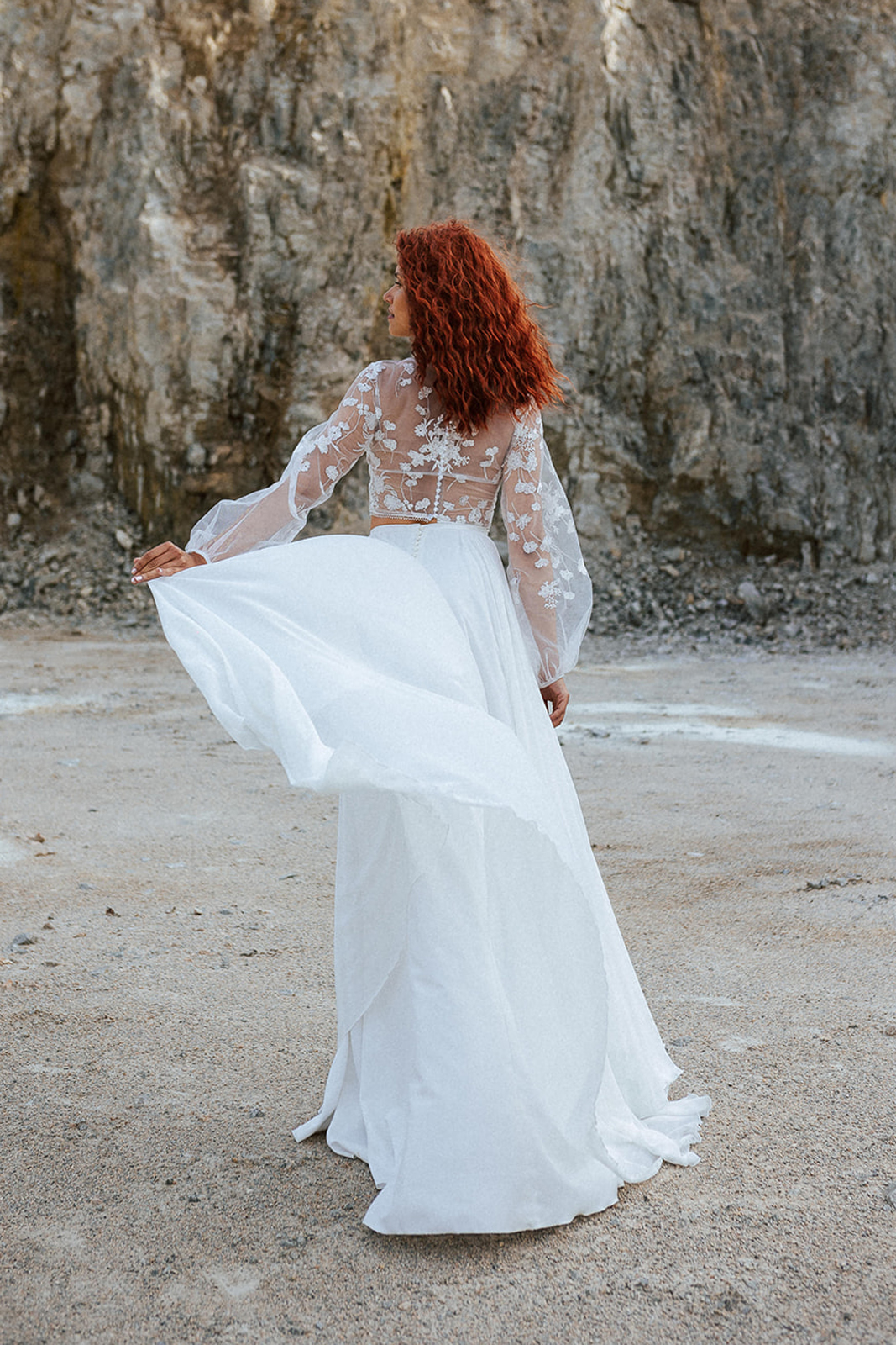Femme rousse portant une robe de mariée bohème de créateur en dentelle sur-mesure.