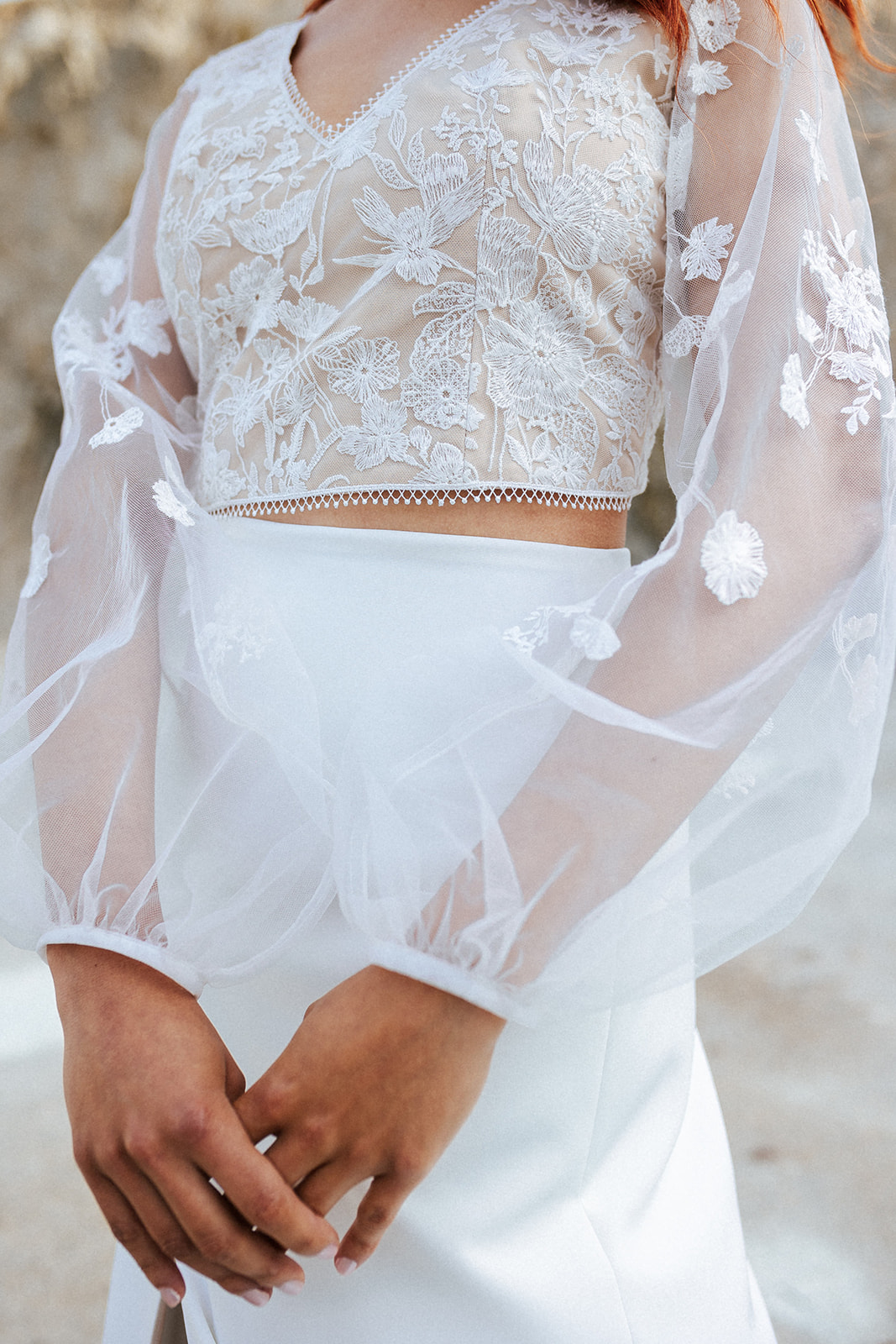 Femme rousse portant une robe de mariée bohème de créateur en dentelle sur-mesure.