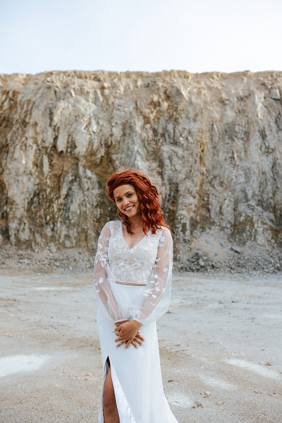 Femme rousse portant une robe de mariée bohème de créateur en dentelle sur-mesure.