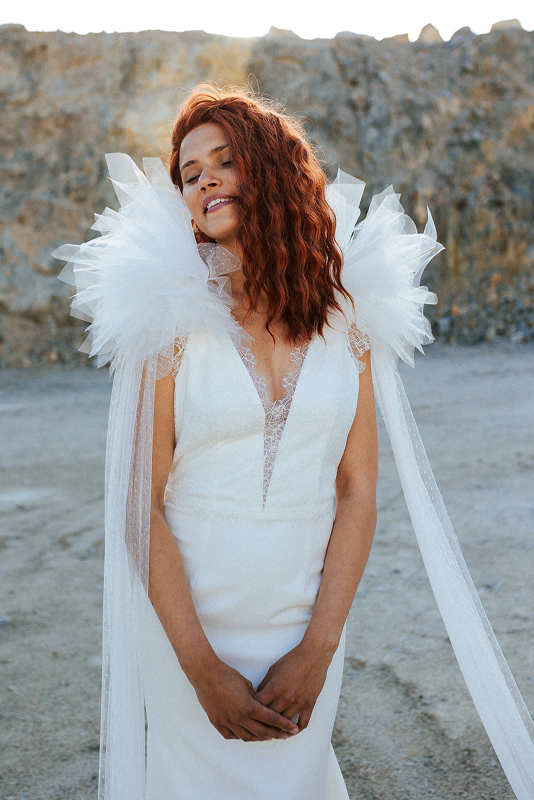Femme rousse portant une robe de mariée originale de créateur en dentelle sur-mesure.