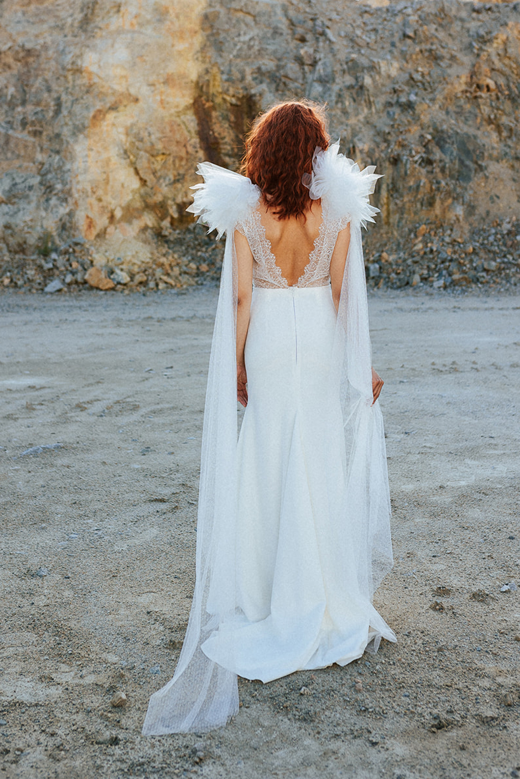Femme rousse portant une robe de mariée originale de créateur en dentelle sur-mesure.