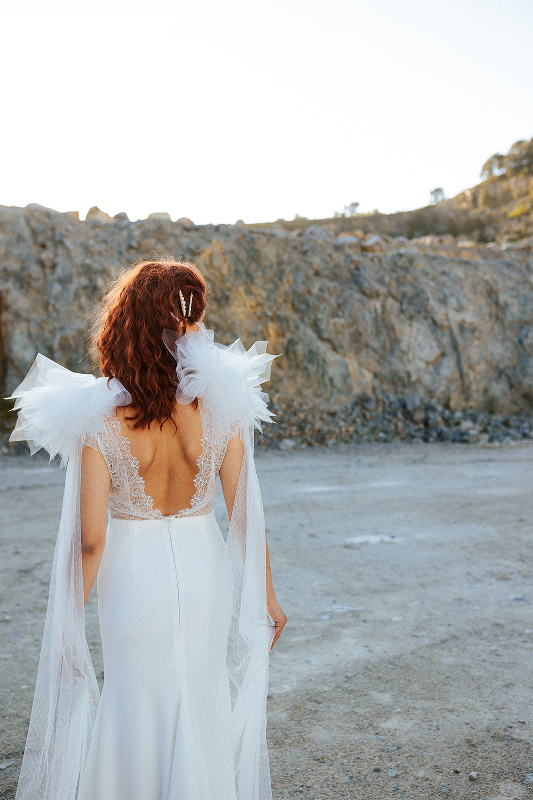 Femme rousse portant une robe de mariée originale de créateur en dentelle sur-mesure.
