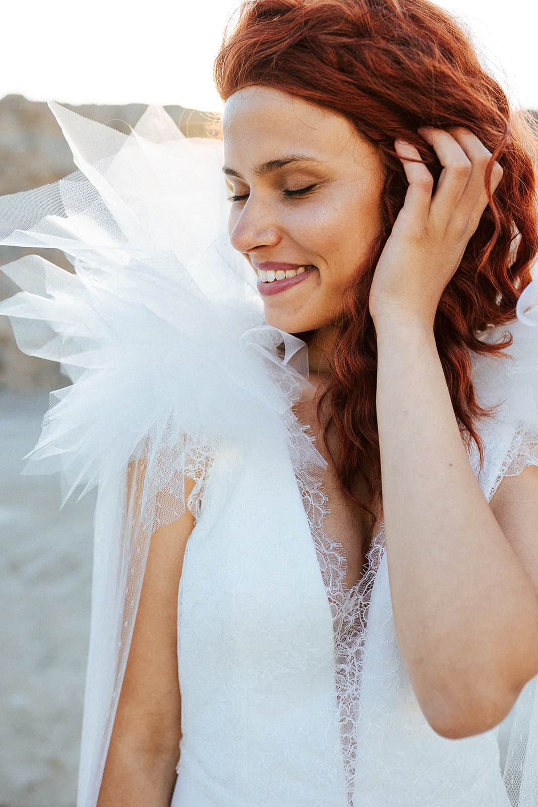 Femme rousse portant une robe de mariée originale de créateur en dentelle sur-mesure.