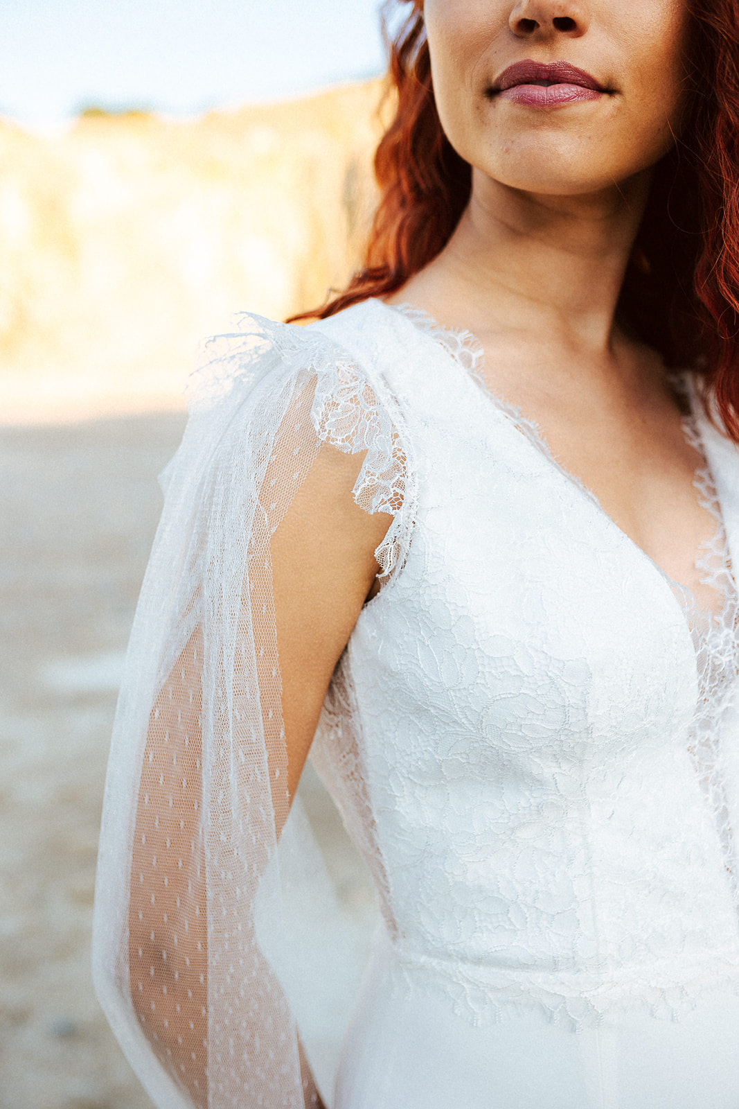 Femme rousse portant une robe de mariée originale de créateur en dentelle sur-mesure.