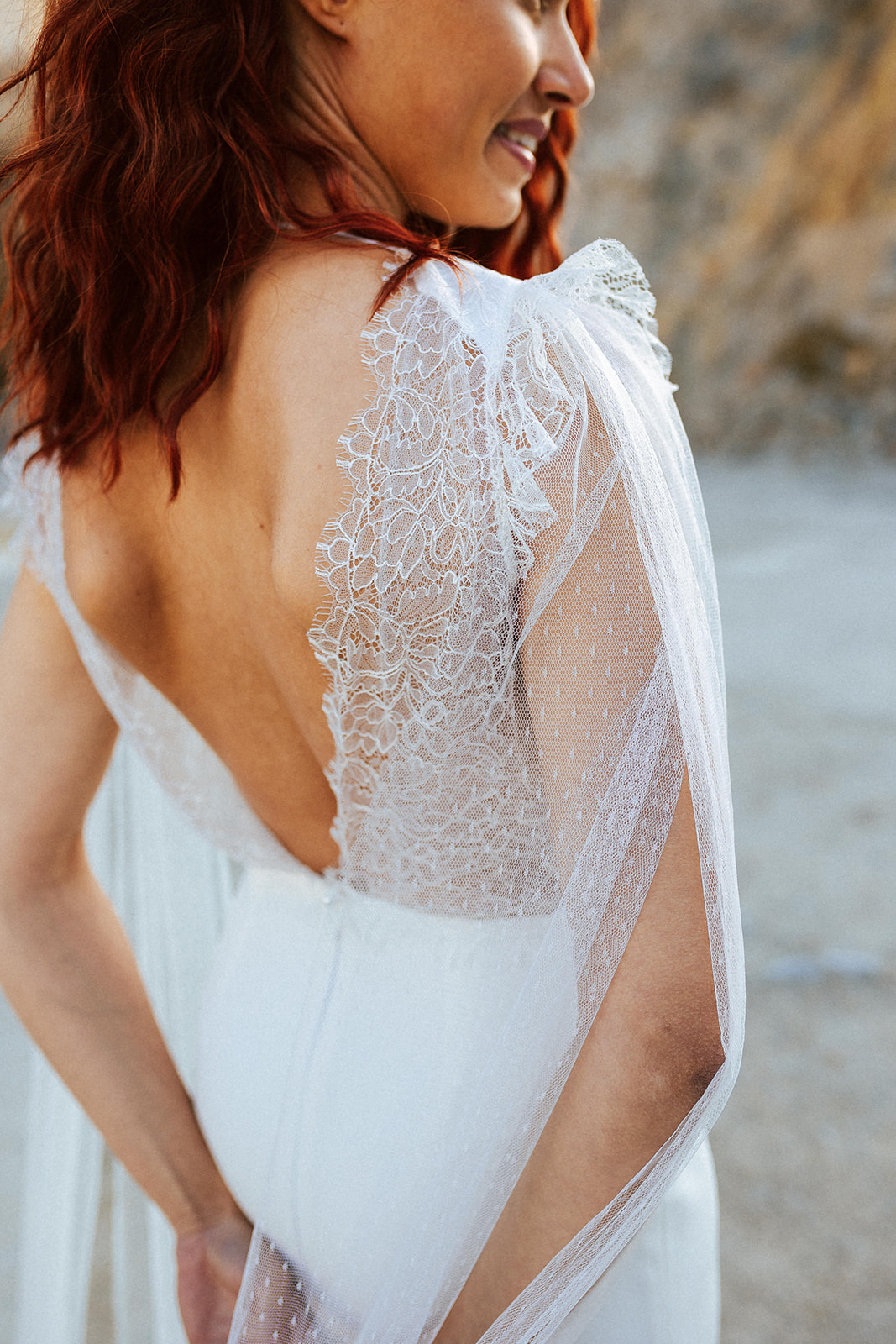 Femme rousse portant une robe de mariée originale de créateur en dentelle sur-mesure.