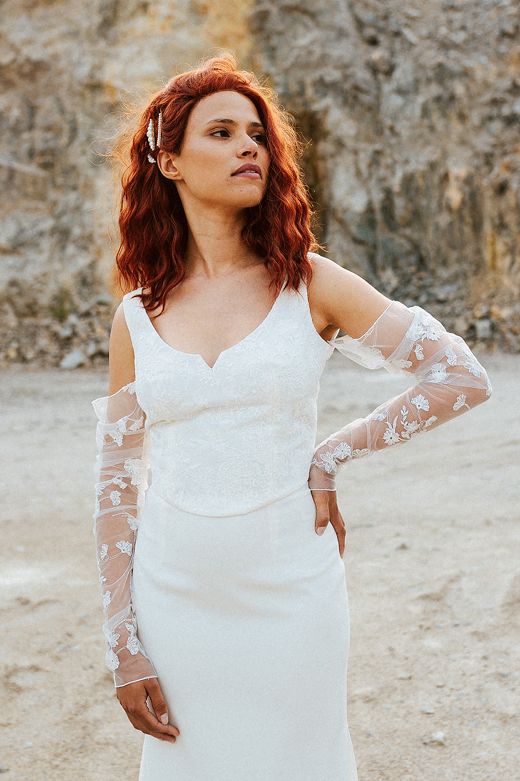 Femme rousse portant une robe de mariée de créateur en dentelle sur-mesure.