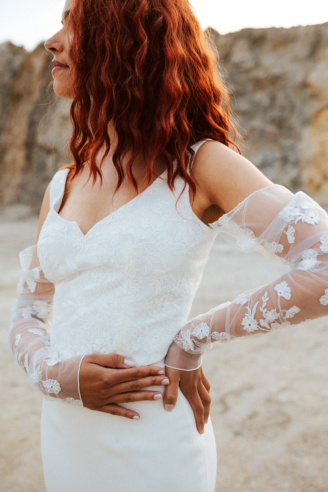 Femme rousse portant une robe de mariée de créateur en dentelle sur-mesure.