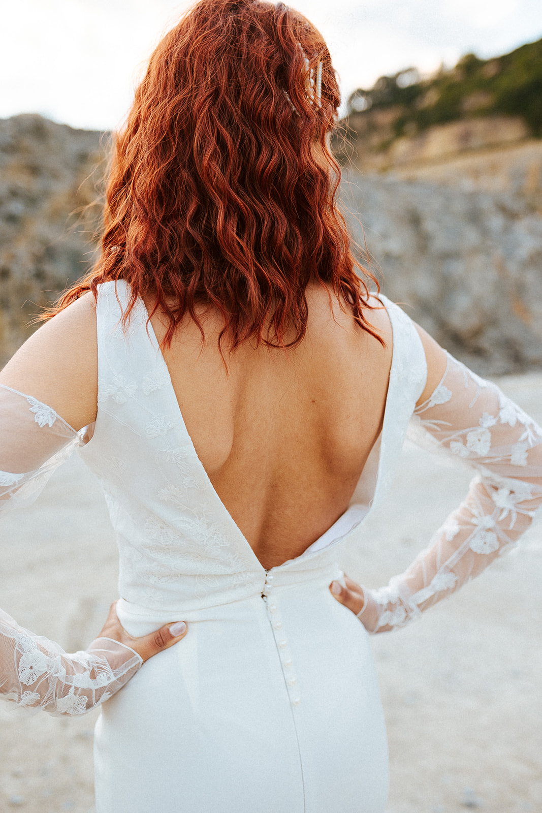 Femme rousse portant une robe de mariée de créateur en dentelle sur-mesure.