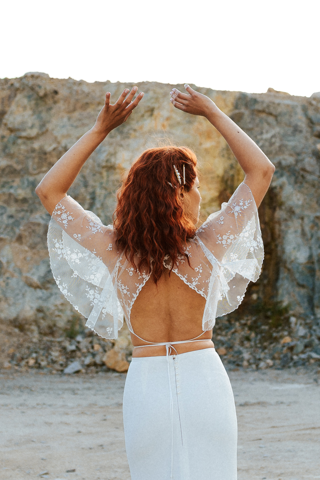 Femme rousse portant une robe de mariée de créateur en dentelle sur-mesure.