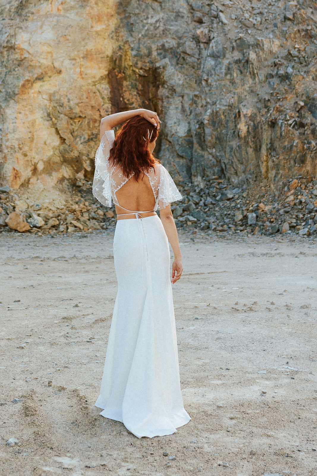 Femme rousse portant une robe de mariée de créateur en dentelle sur-mesure.