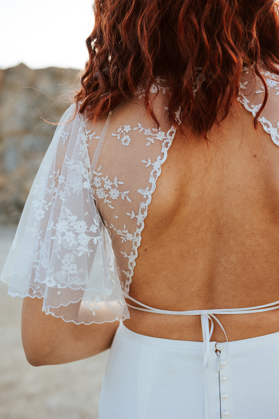 Femme rousse portant une robe de mariée de créateur en dentelle sur-mesure.