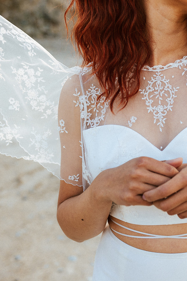 Femme rousse portant une robe de mariée de créateur en dentelle sur-mesure.
