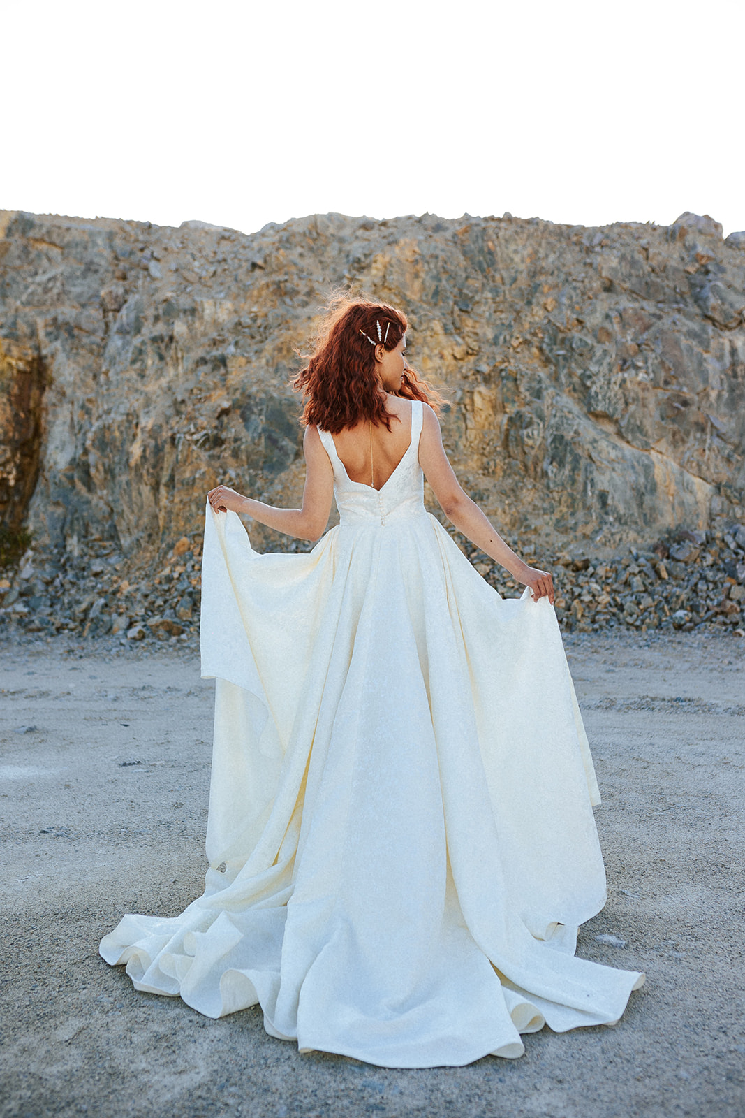 Femme rousse portant une robe de mariée de créateur asymétrique sur-mesure.