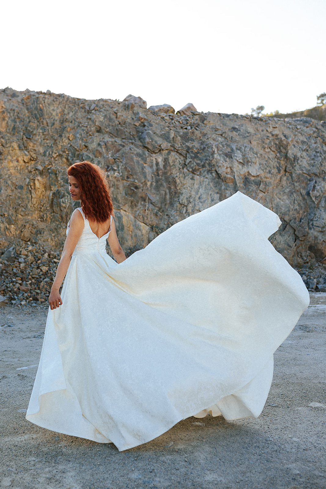 Femme rousse portant une robe de mariée de créateur asymétrique sur-mesure.