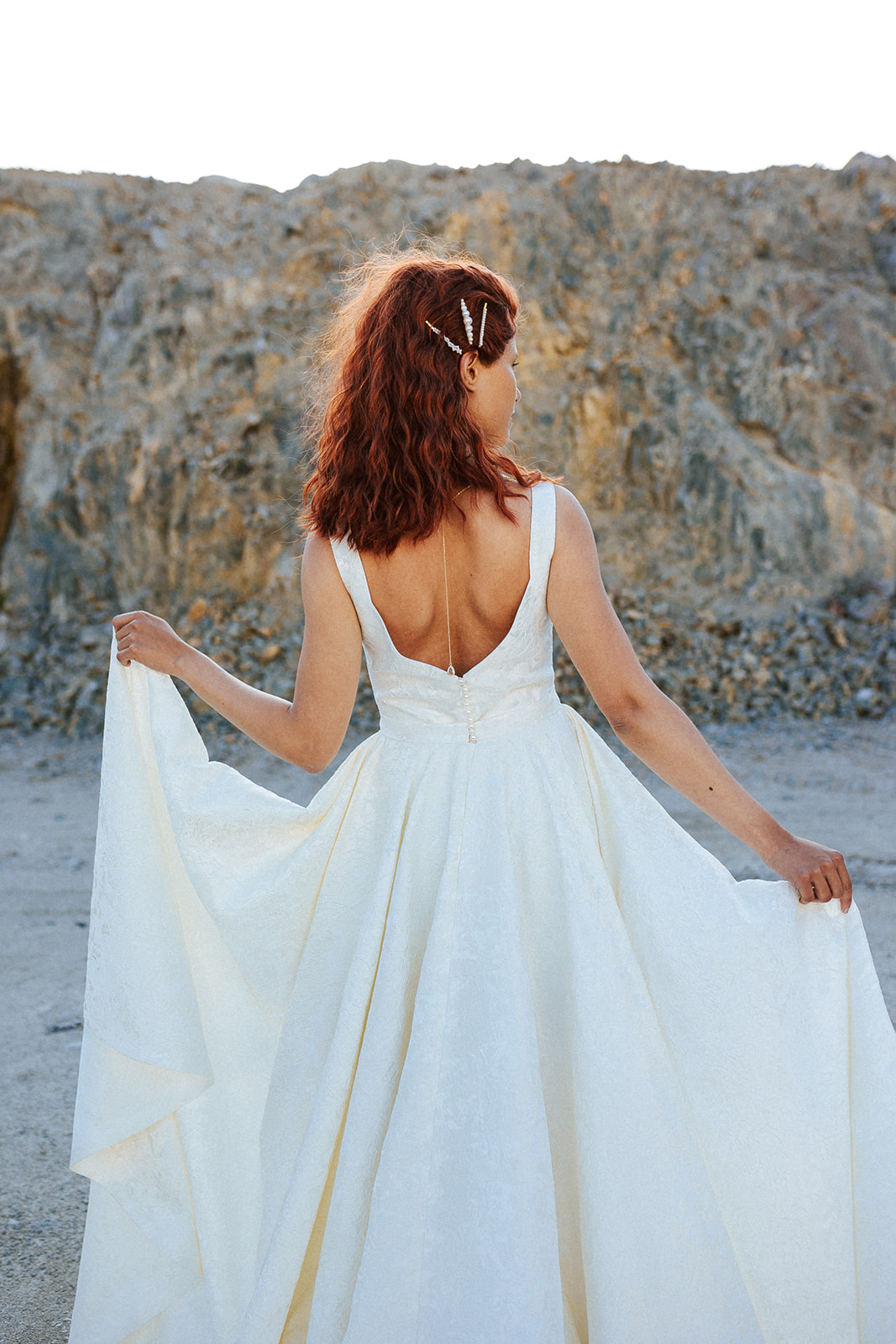 Femme rousse portant une robe de mariée de créateur asymétrique sur-mesure.